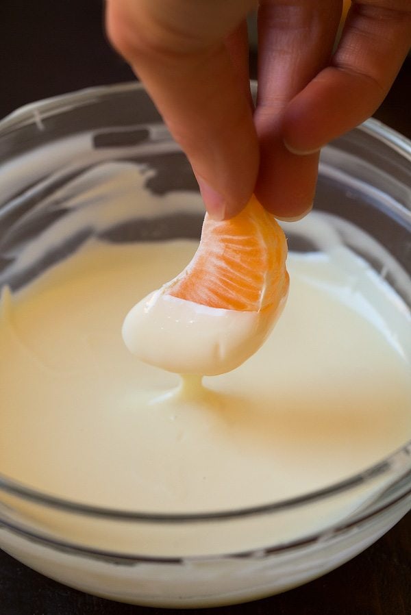 Chocolate Dipped Oranges Dipping mandarin orange in melted white chocolate.