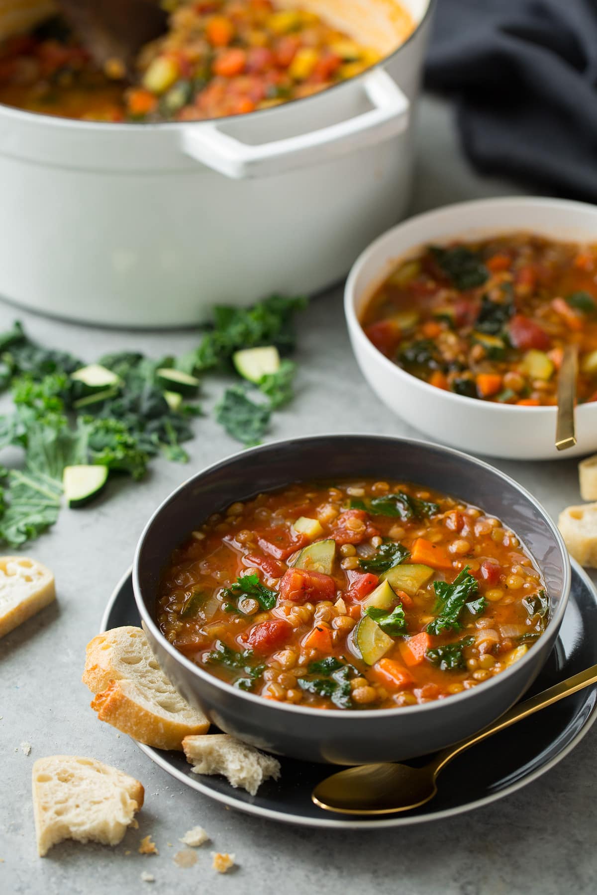 Lentil Soup Lenti Soup shown here in an individual serving in a grey bowl set over a grey plate with a second serving in the background