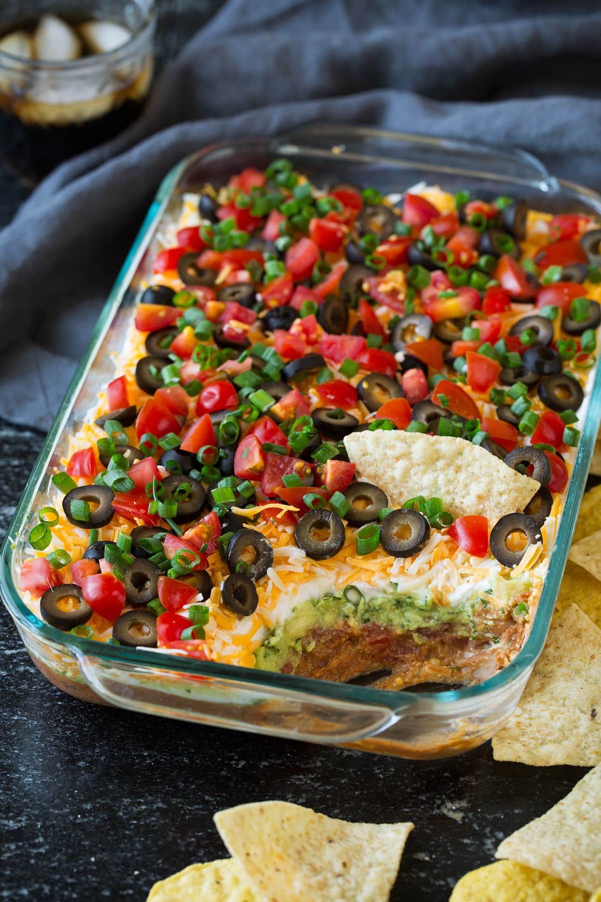 7 Layer Bean Dip - one of the all time best party foods! This stuff is addictive! #7layerdip #dip #appetizer #snack #partyfood 7 Layer Dip in a glass baking dish.