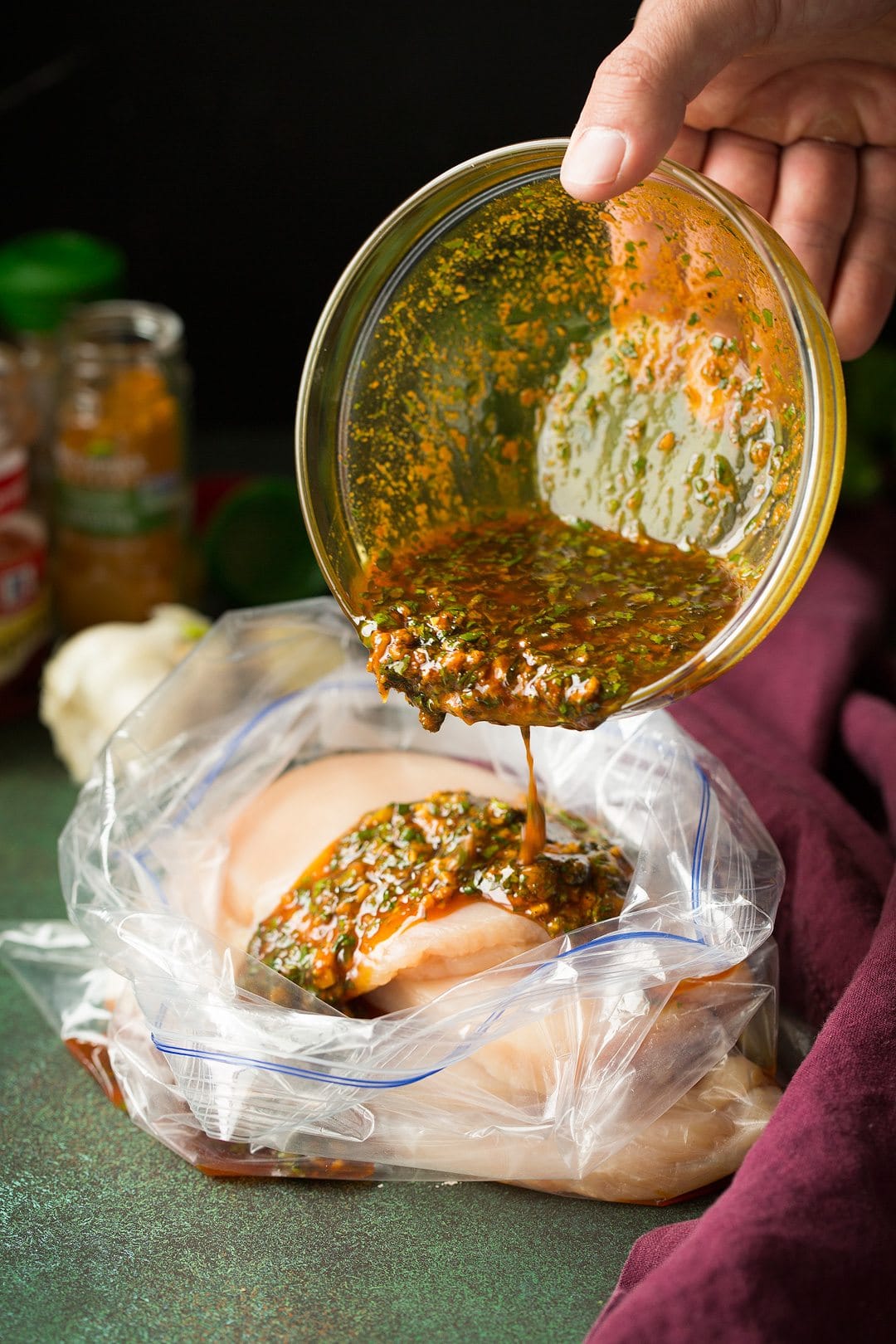 Moroccan Chicken Pouring marinade over chicken breasts in a large resealable bag.