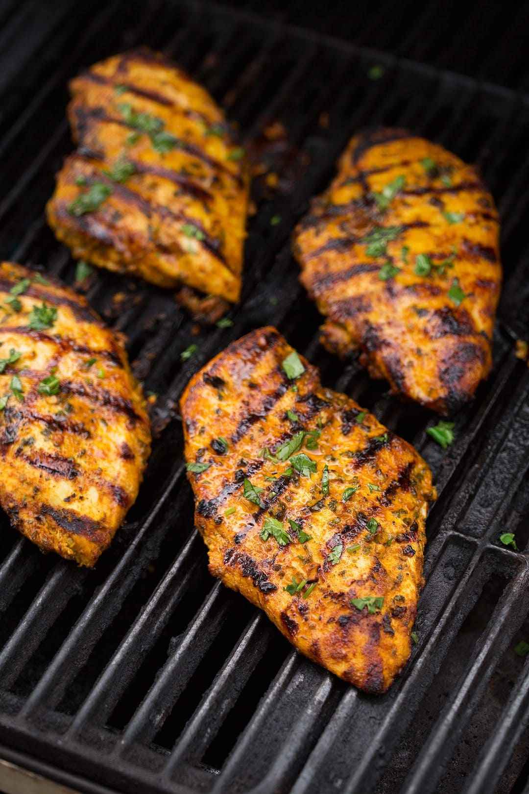 Grilled Moroccan Chicken Four boneless skinless chicken breasts cooking on grill.