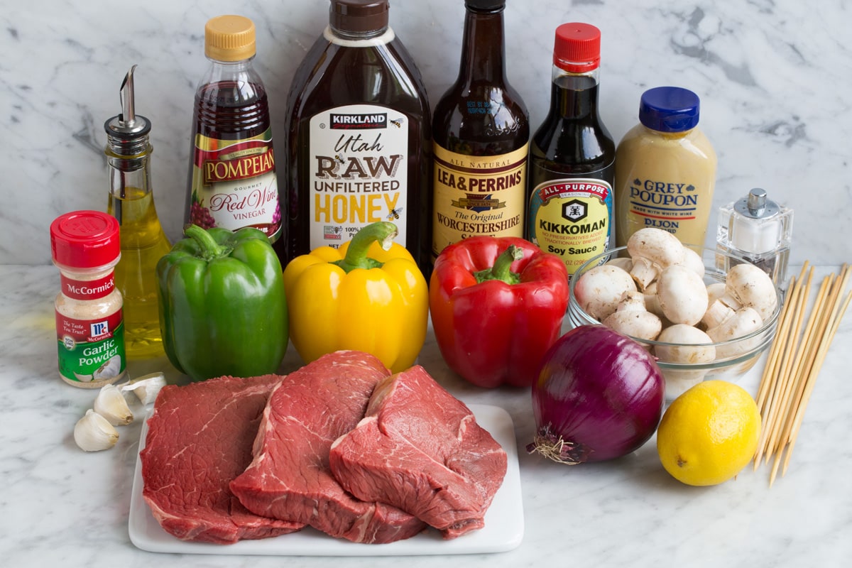 Steak Kebabs - super delicious and perfect for summer! Ingredients needed to make steak kebabs shown here including steaks, bell peppers, red onion, garlic, lemon, dijon mustard, soy sauce, Worcestershire, honey, red wine vinegar, olive oil, garlic powder.