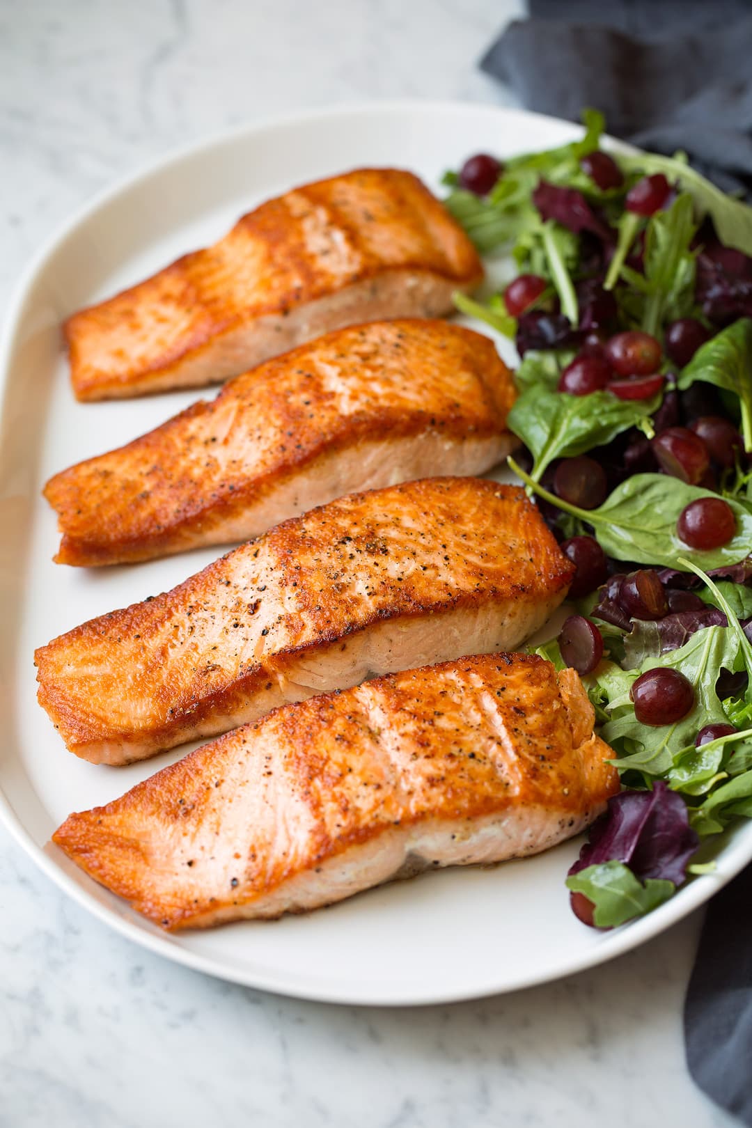 pan seared salmon fillets on platter with salad