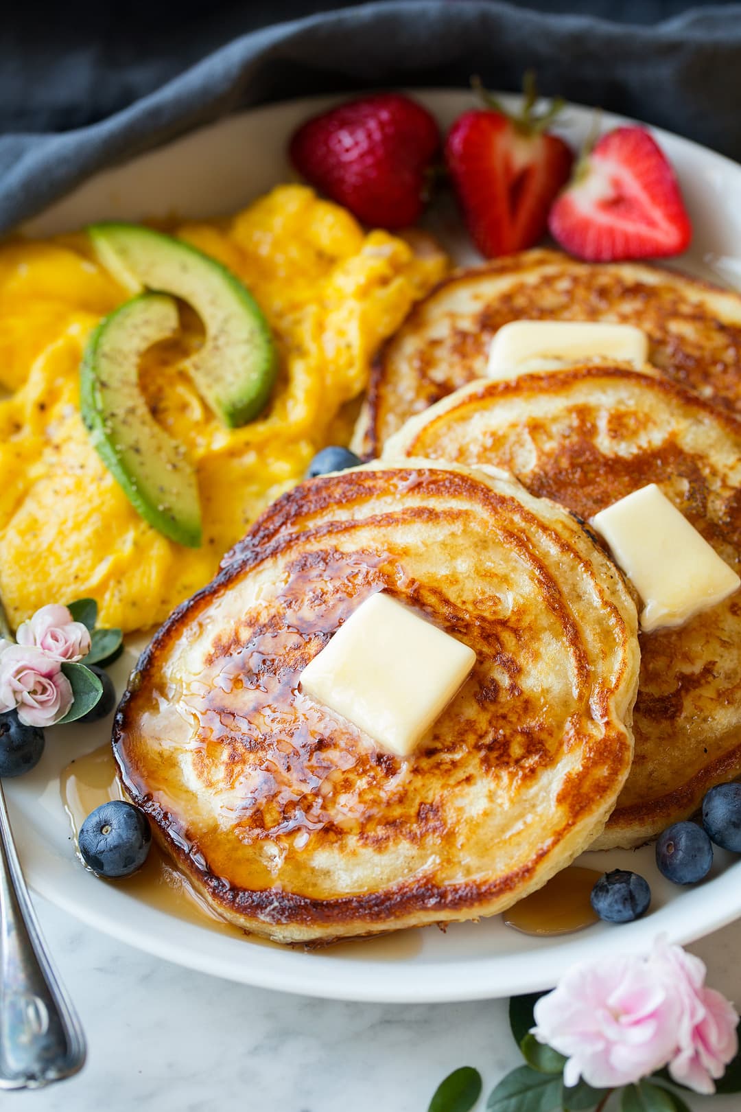 Buttermilk Pancakes Close up image of buttermilk pancakes with perfect golden brown edges, maple syrup and butter.