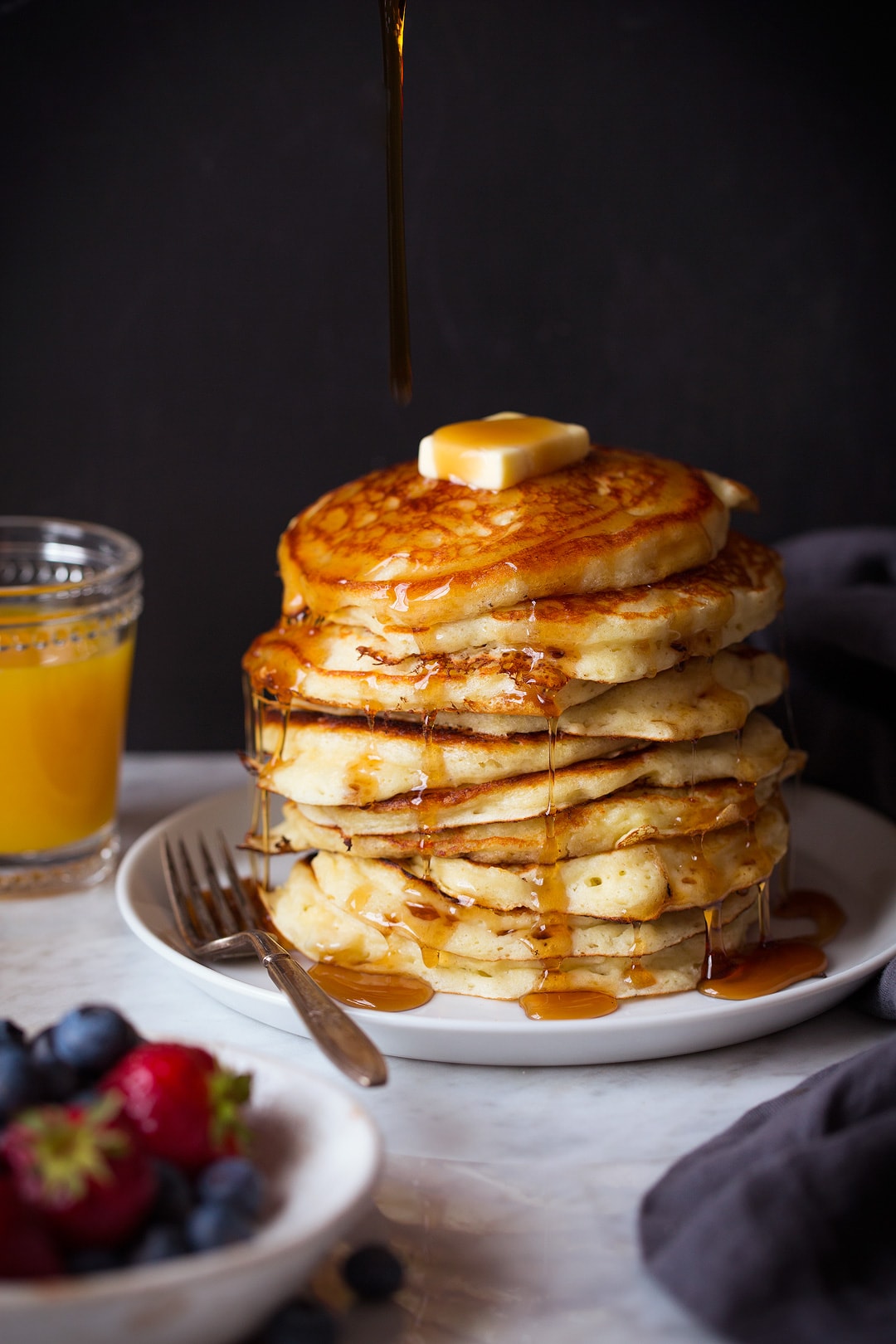 Cooking Classy Stack of pancakes on a plate. Syrup is being poured over the top.