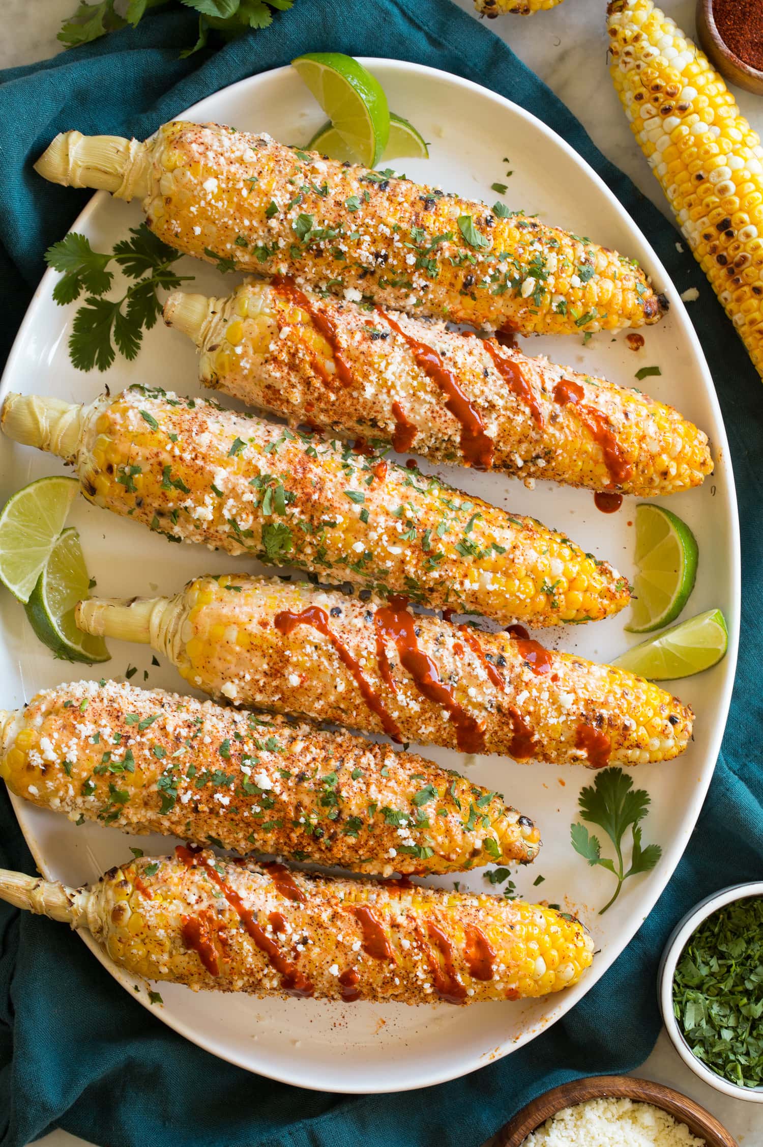Grilled Mexican Street Corn Elotes Overhead image of grilled Mexican street corn on white oval platter.