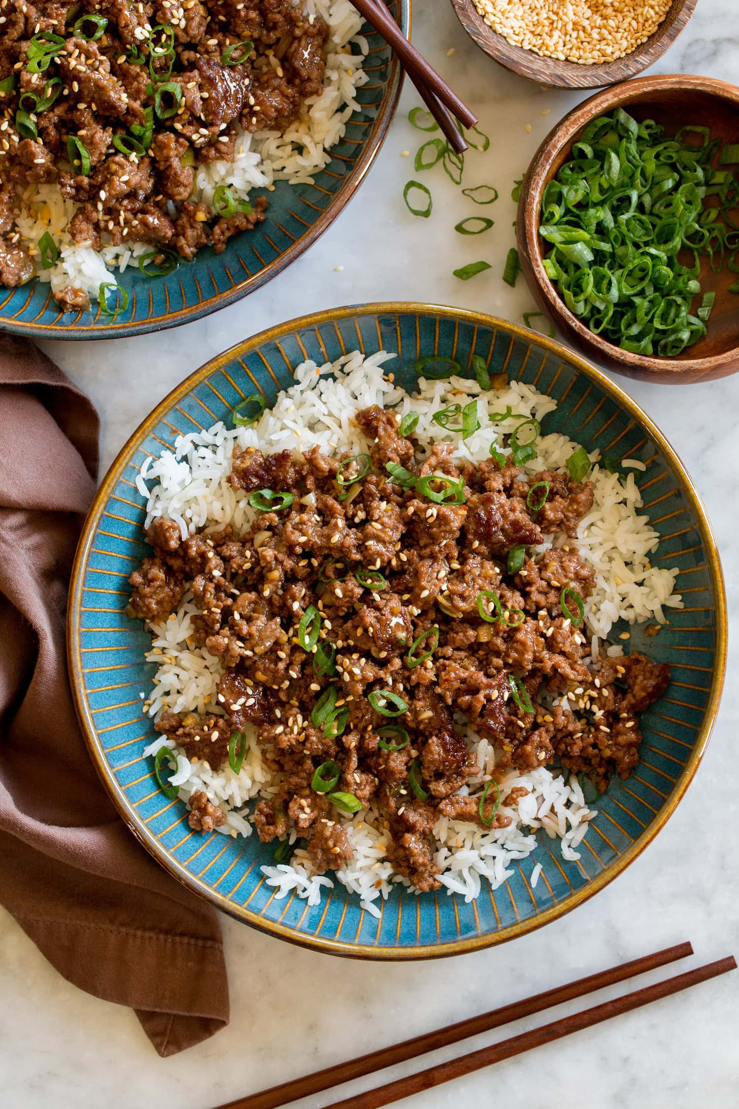 Korean Beef Bowls Korean beef in a blue bowl with white rice and green onions. Shown from overhead.