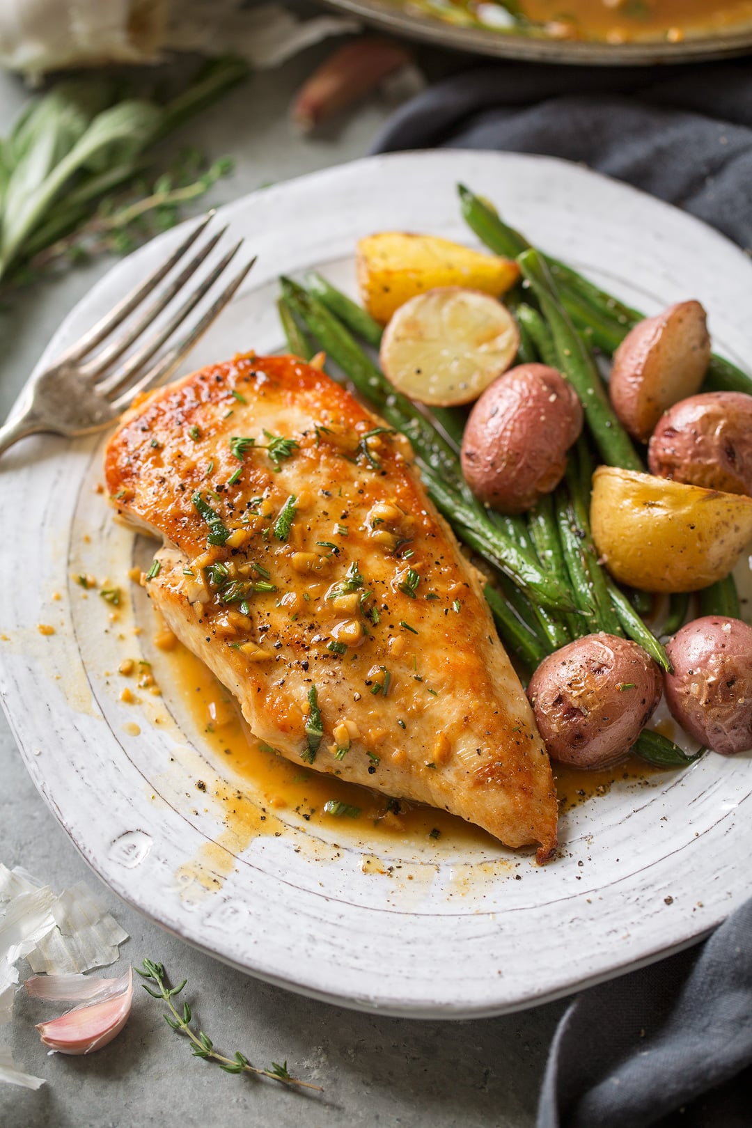 Super quick and easy seared skillet chicken topped with a delicious garlic and herb pan sauce that's sure to please! A perfect chicken recipe for busy weeknights. | Chicken Dinner | Chicken Recipes | Weeknight Meals | #cookingclassy #chicken #sauce #butter Skillet Chicken with Garlic Herb Butter Sauce on a plate with roast vegetables