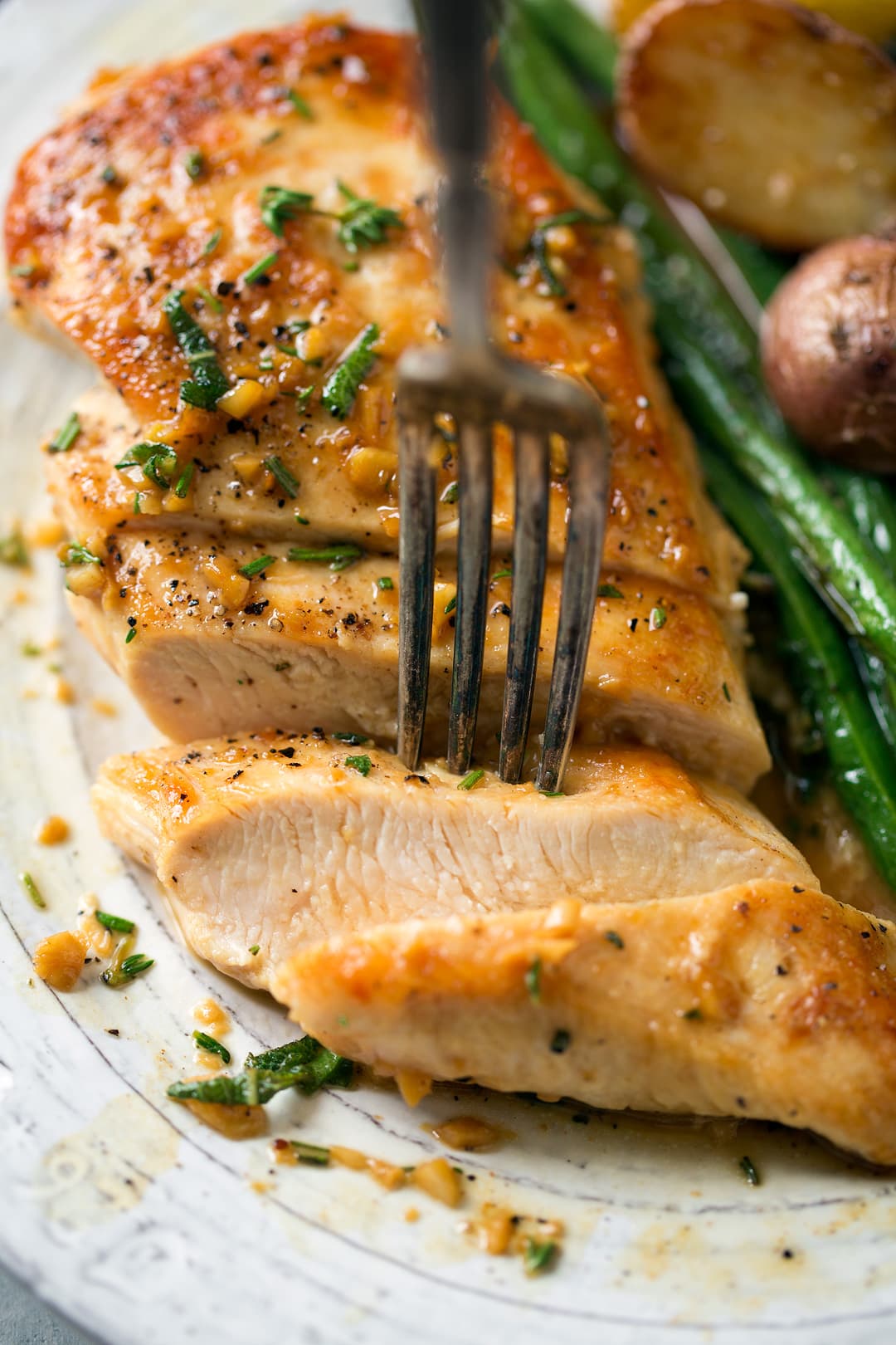 Super quick and easy seared skillet chicken topped with a delicious garlic and herb pan sauce that's sure to please! A perfect chicken recipe for busy weeknights. | Chicken Dinner | Chicken Recipes | Weeknight Meals | #cookingclassy #chicken #sauce #butter Skillet Chicken cut into slices with a fork picking up a piece
