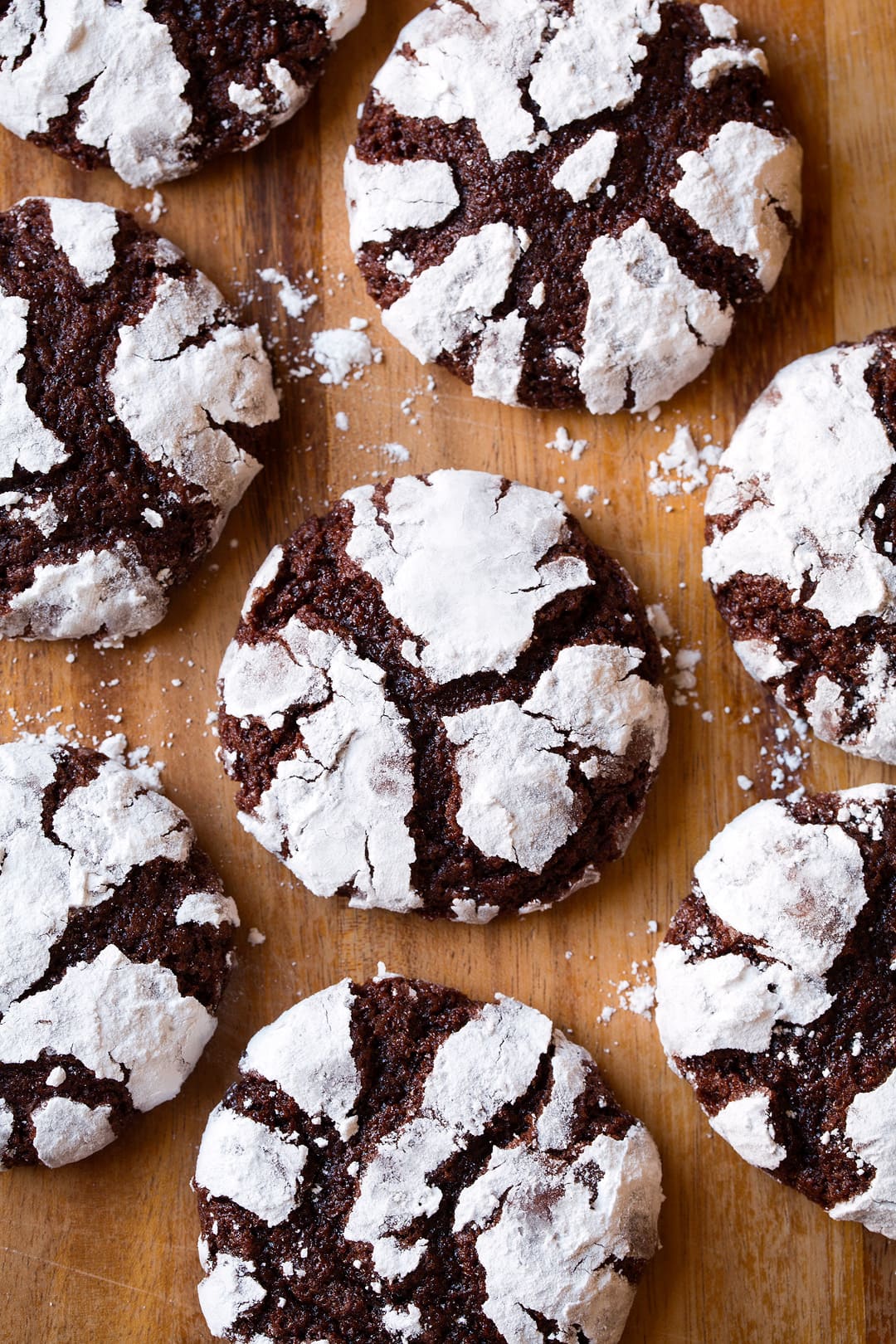 Chocolate Crinkle Cookies Chocolate Crinkle Cookies shown overhead laying on a wooden surface.
