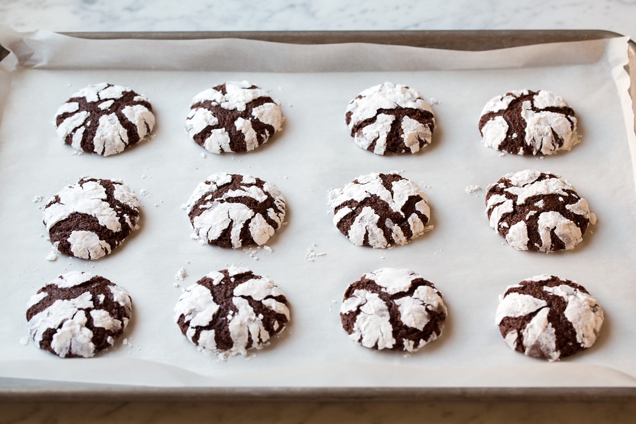 Chocolate Crinkle Cookies Chocolate Crinkle Cookies shown on parchment paper baking sheet after baking.