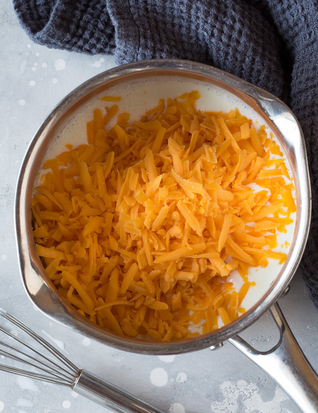 cheddar cheese and half and half in metal saucepan