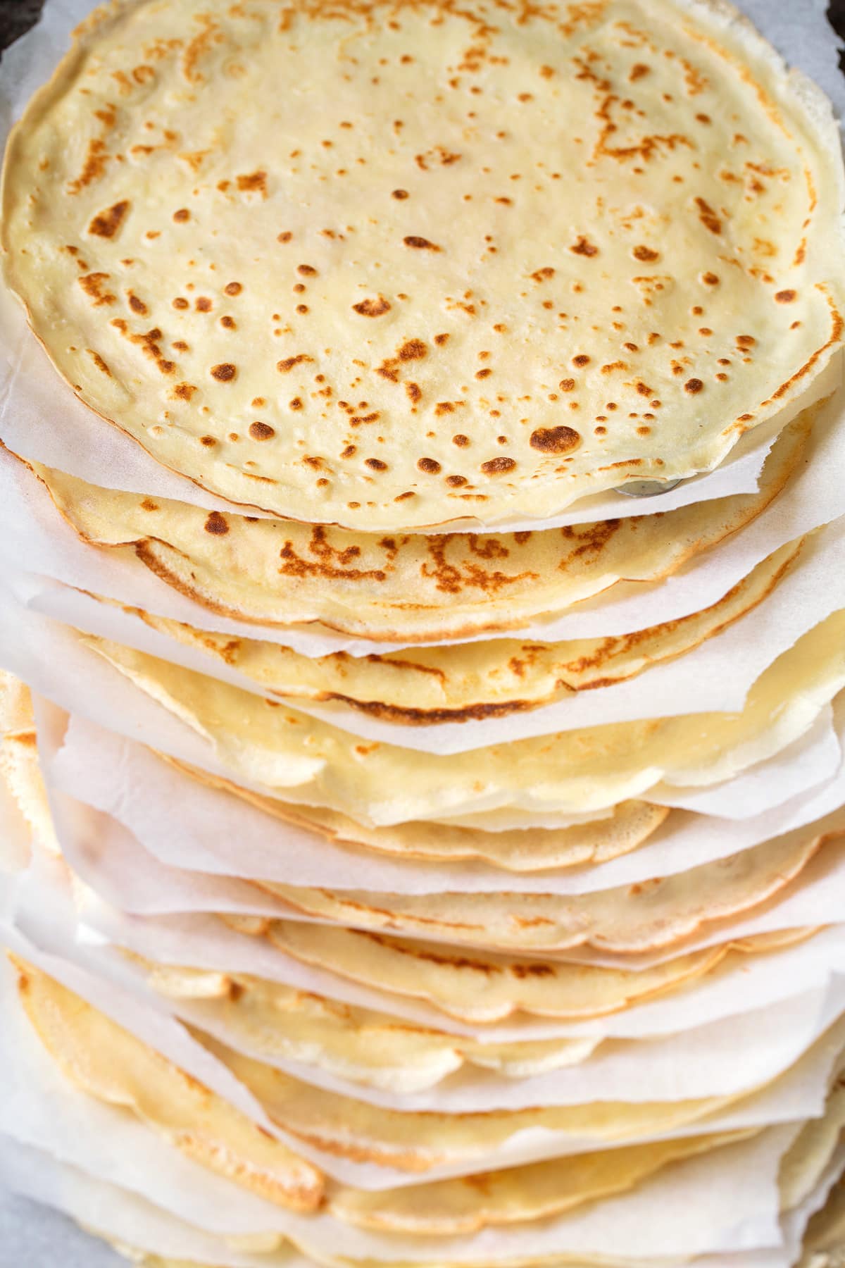 Crepes Recipe Stack of homemade crepes with parchment paper between each.