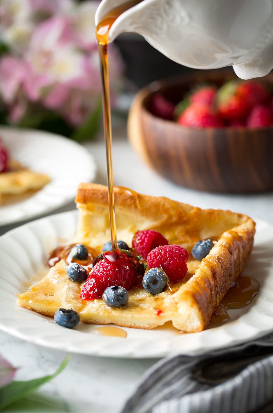 drizzling maple syrup onto a slice of German Pancake