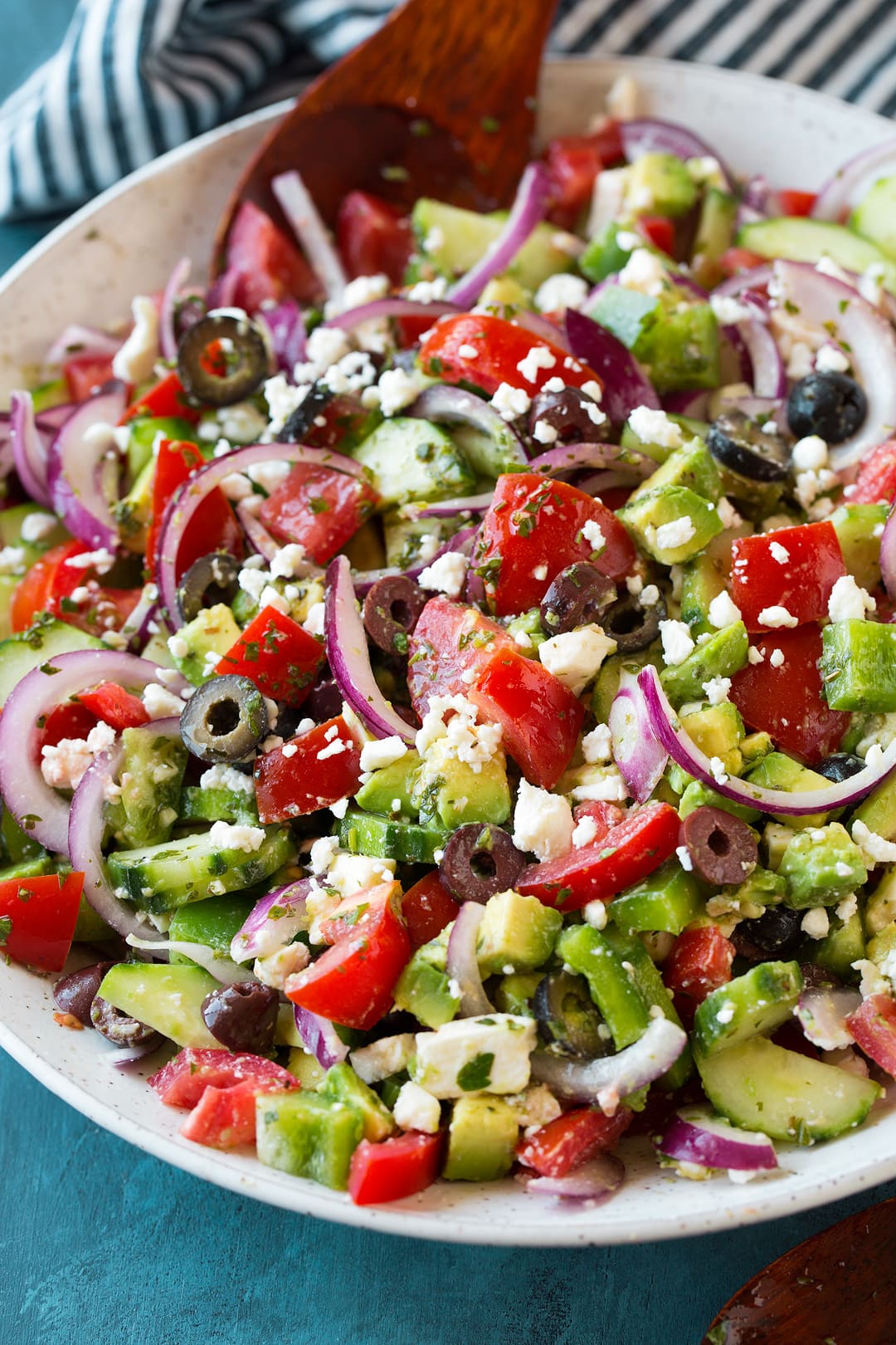 Greek Salad - this is the BEST Greek Salad! So easy to make, it's packed with veggies (love the addition of avocado), and the dressing is so flavorful. A must try recipe! #greek #salad #recipe #vegetables #sidedish #summer Close up photo of a Greek Salad in a white bowl