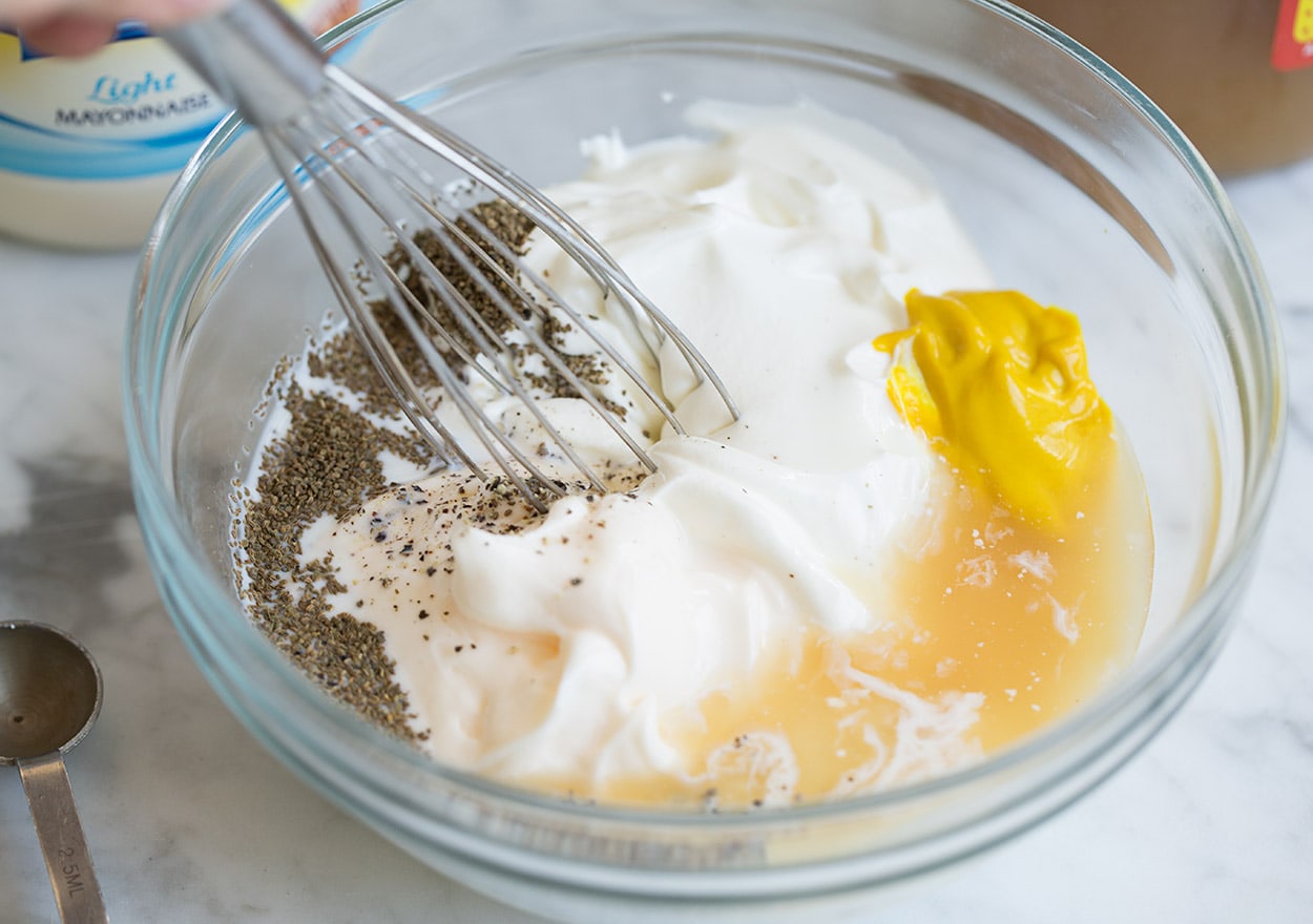 potato salad dressing mixture in a bowl with a whisk