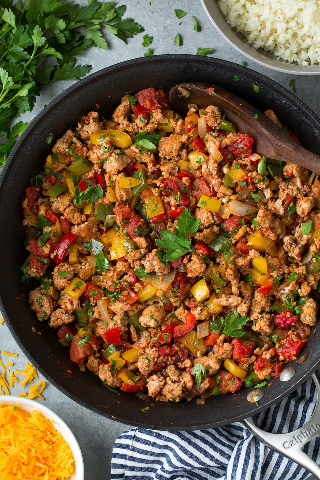 Unstuffed Pepper Bowls with Cauliflower Rice Unstuffed Pepper mixture of ground turkey, peppers and parsley shown here in a dark skillet on a grey surface