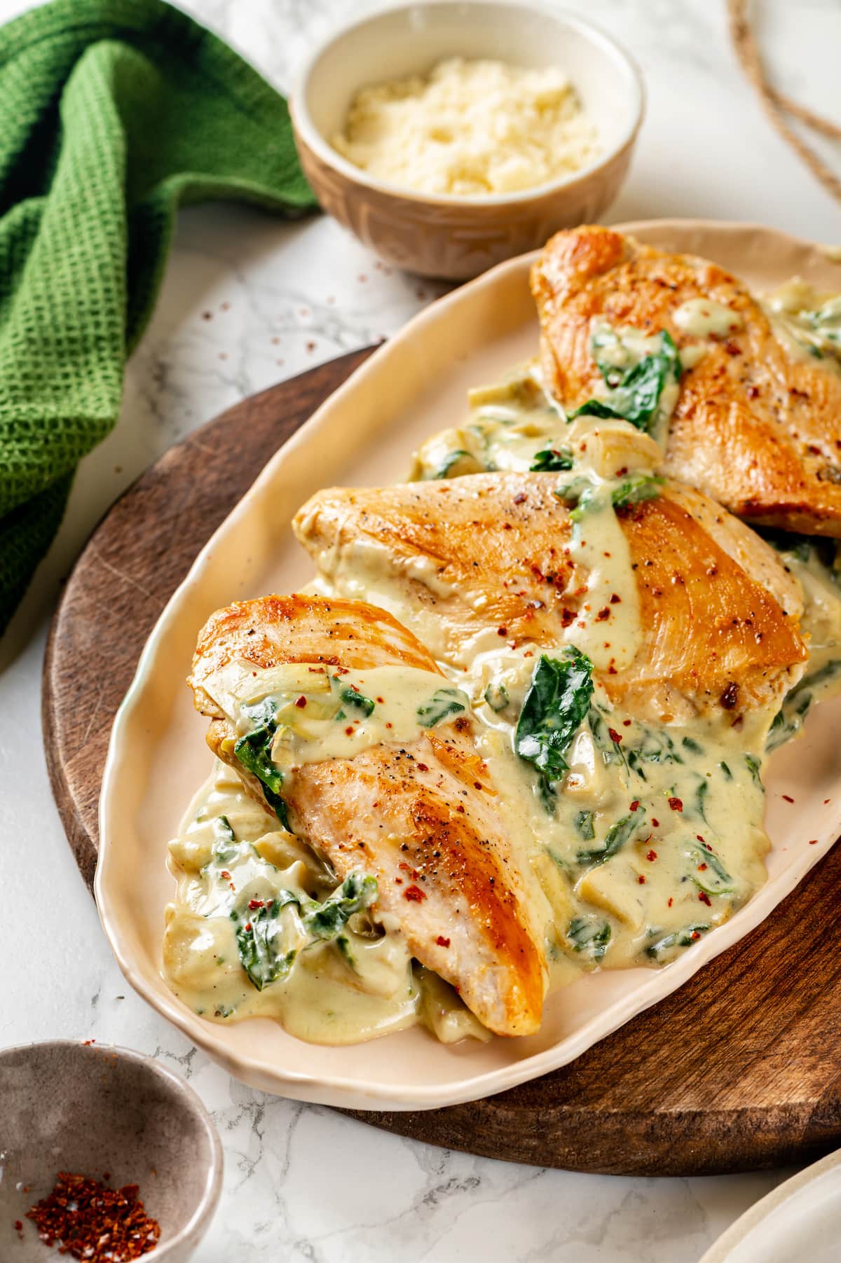 Creamy spinach artichoke chicken is a fast and easy one-pan dinner recipe brimming with briny artichokes, spinach, and lots of melty cheese. Creamy spinach artichoke chicken served on an oval platter.