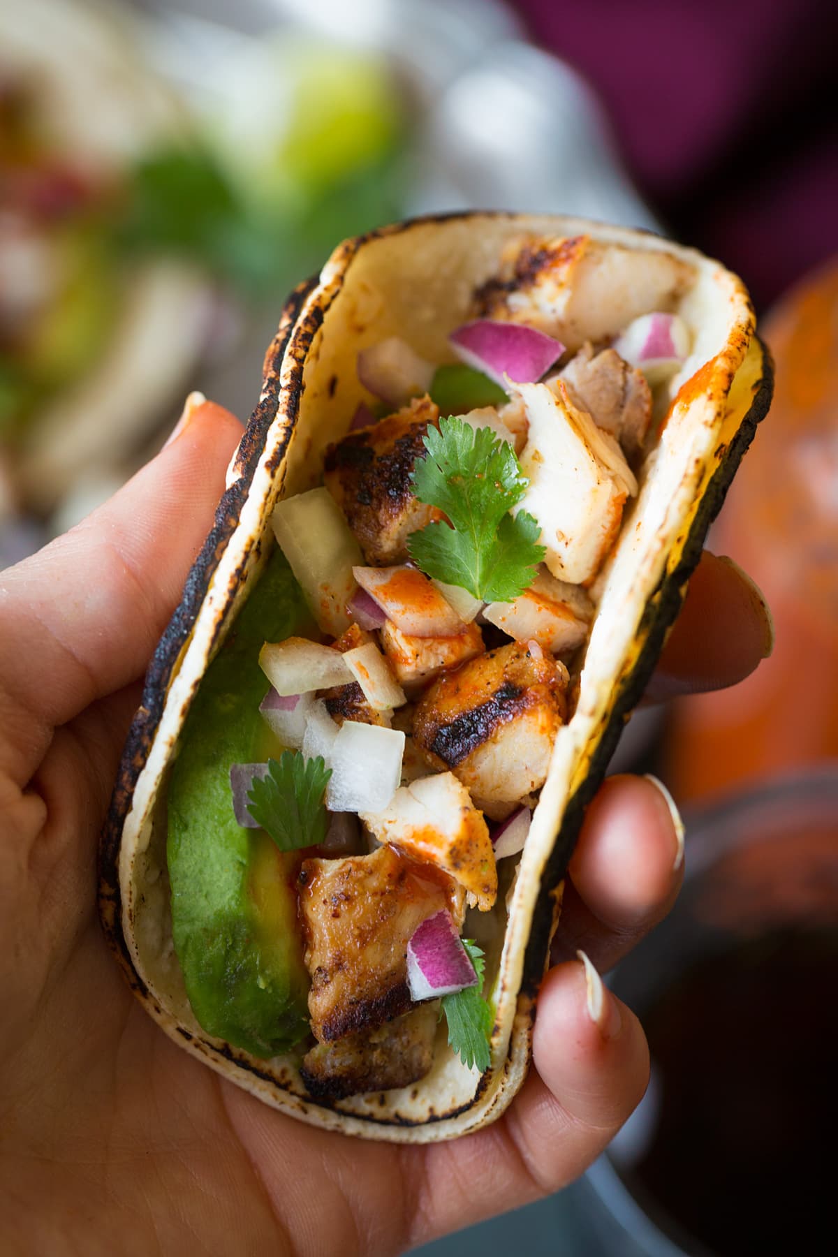 Hand holding a mini street taco, shown close up.