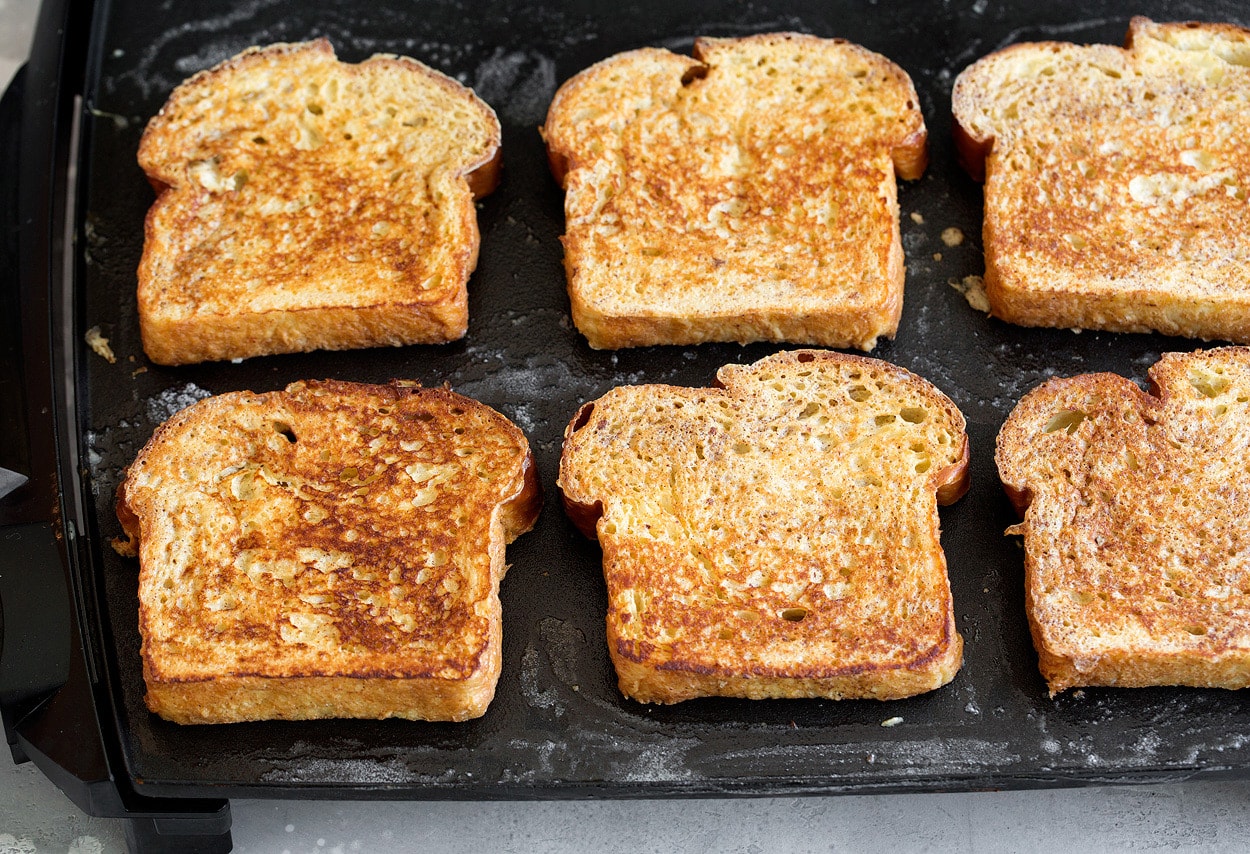 French Toast Showing how to cook french toast. Six slices with golden brown tops are being cooked on an electric griddle.
