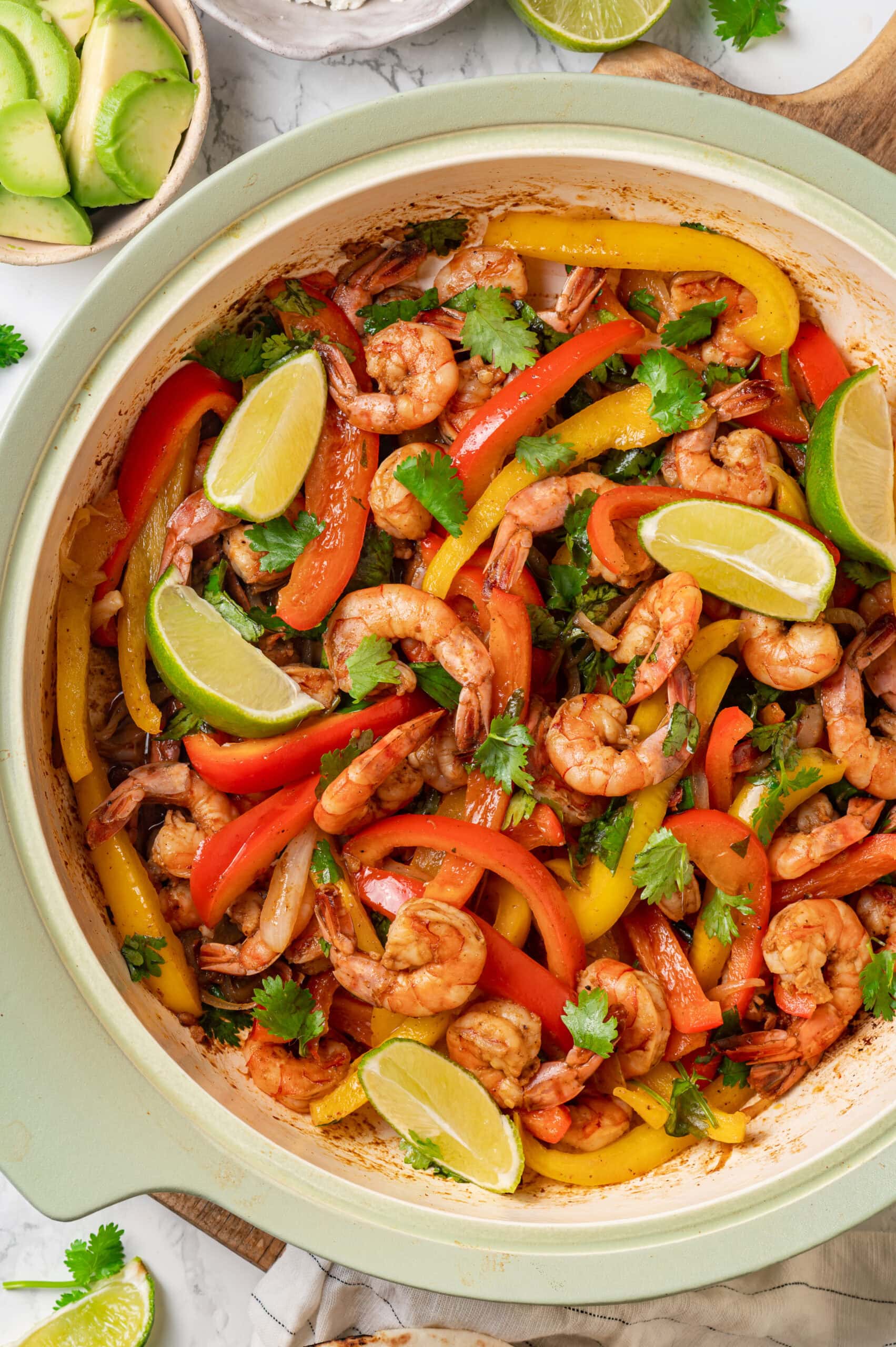 Completed shrimp fajita mixture shown in a skillet overhead with limes.