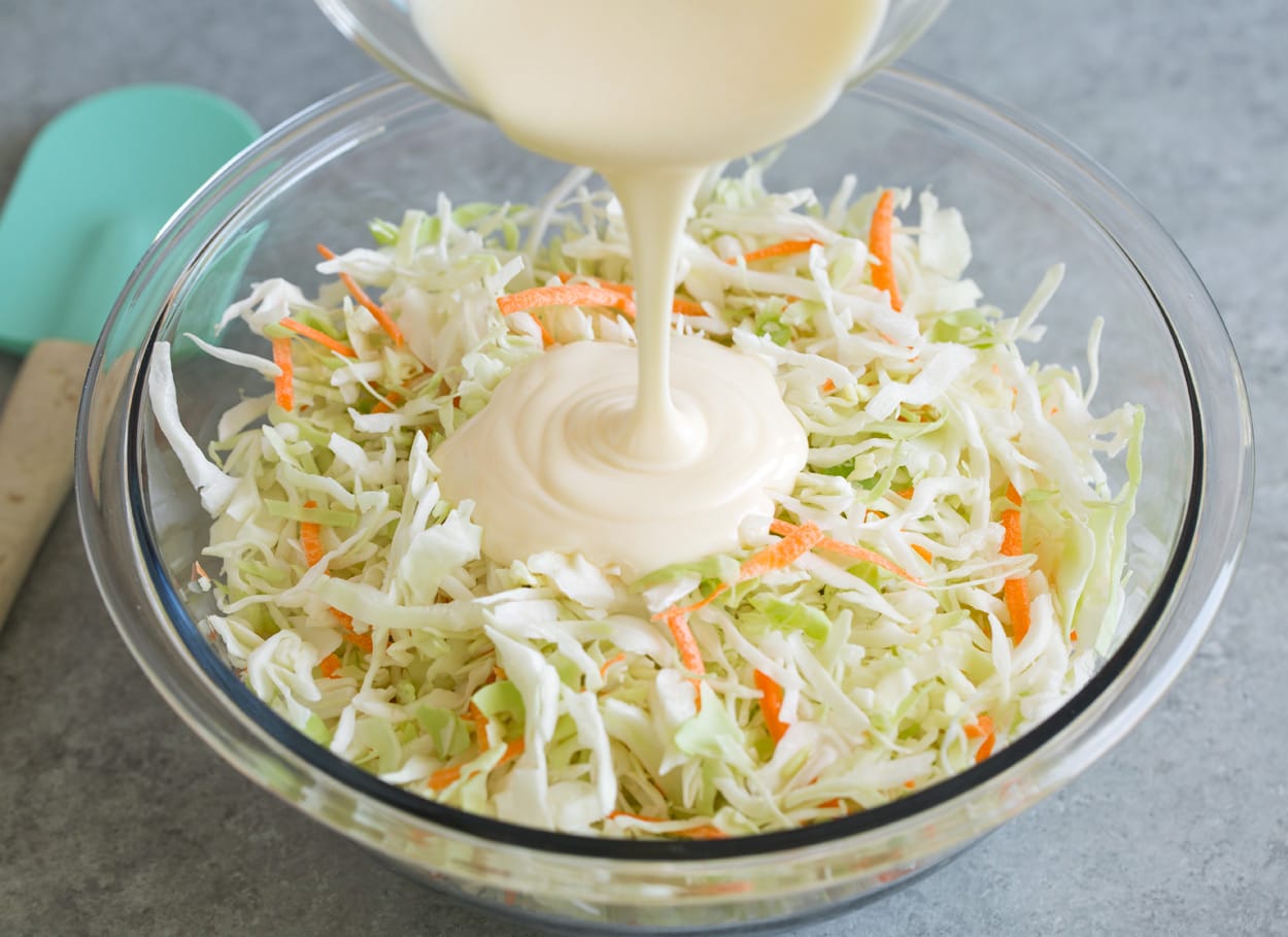 Coleslaw Recipe Adding coleslaw dressing to coleslaw in mixing bowl.