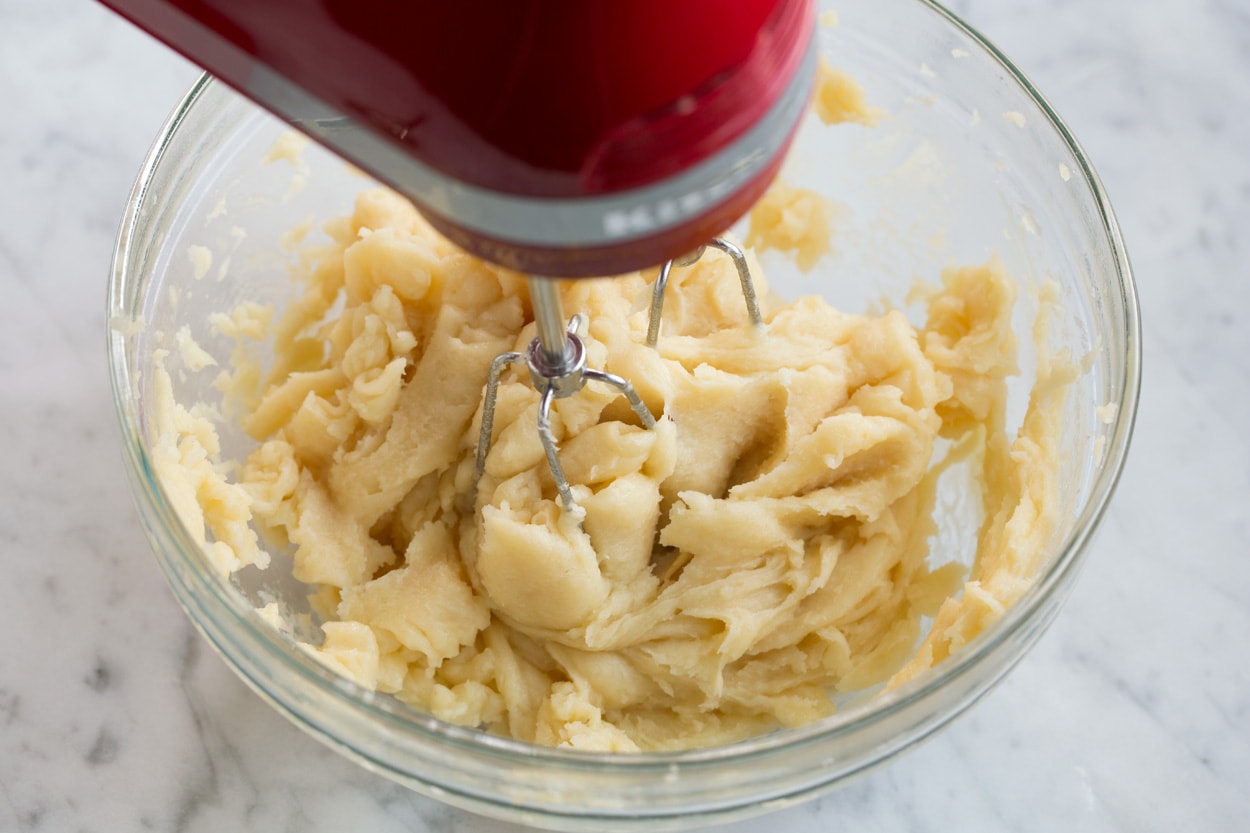 churro batter in mixing bowl mixing with electric hand mixer