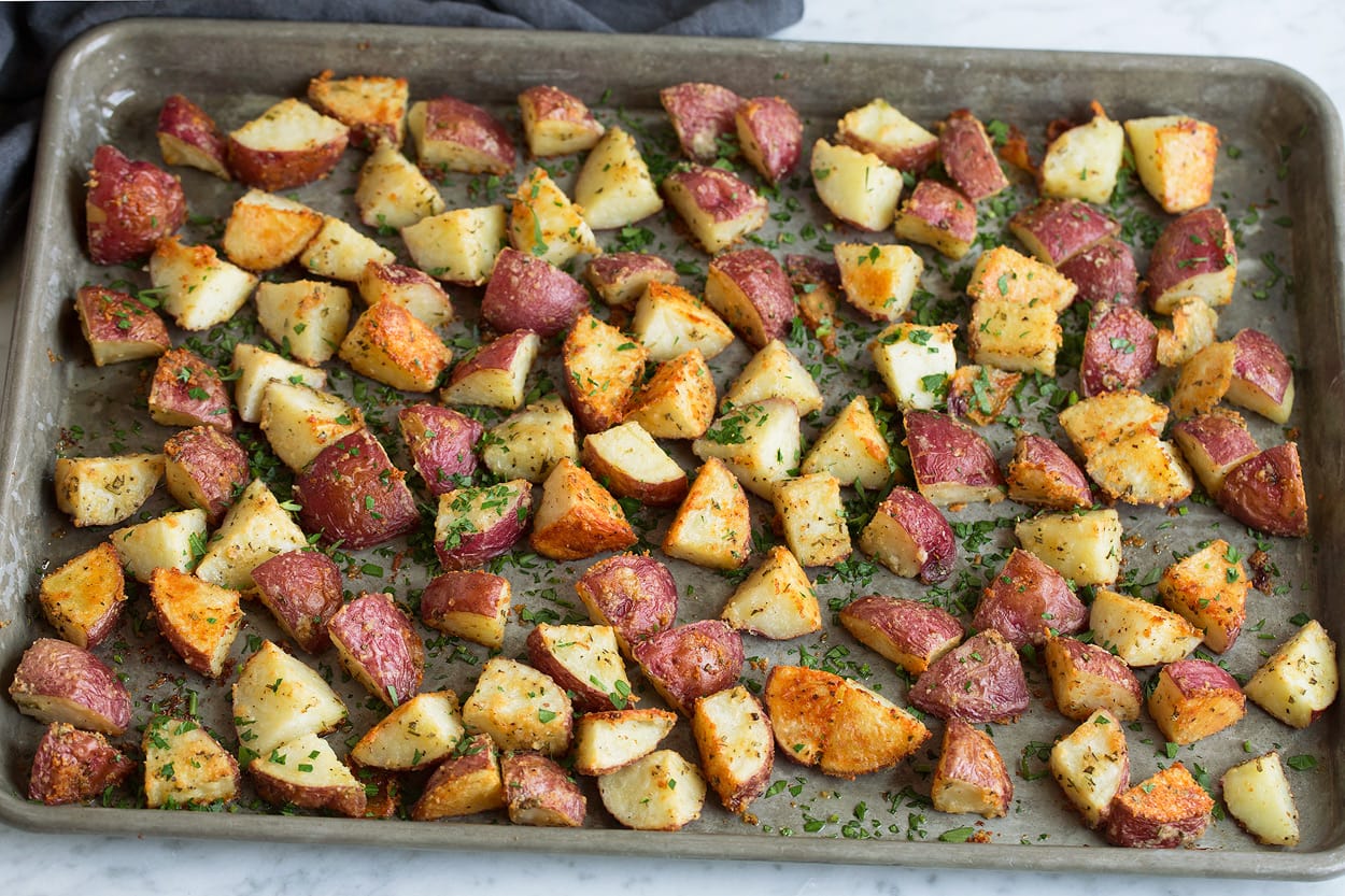 Roasted Potatoes with Garlic Parmesan and Herbs parmesan roasted potatoes on baking dish after roasting in oven showing their golden brown color.