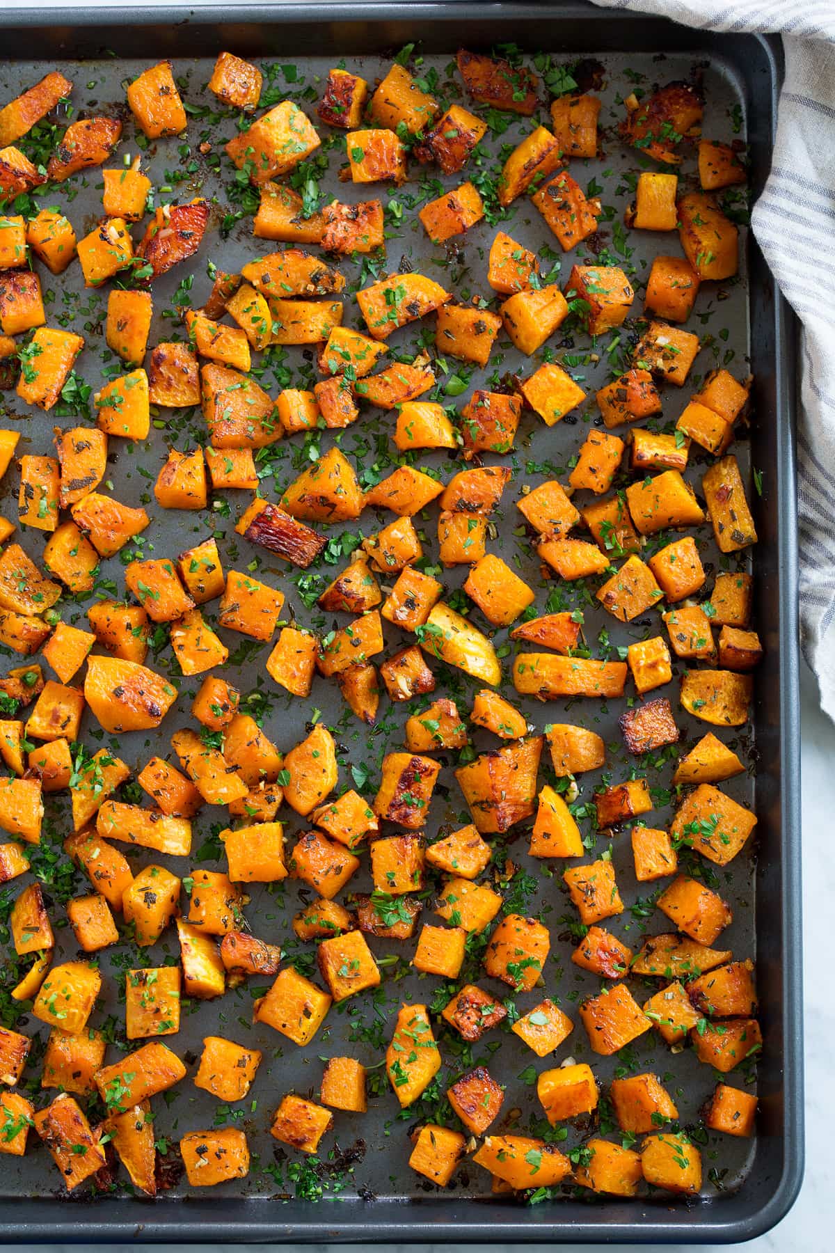 Roasted Butternut Squash with Garlic and Herbs Roasted Butternut Squash on a dark baking sheet after roasting.