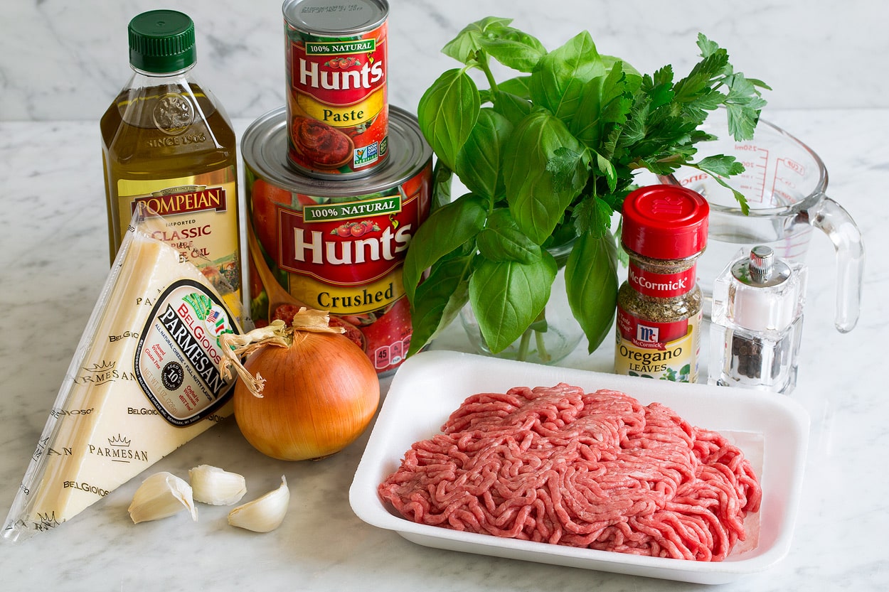 Homemade Spaghetti Sauce Spaghetti Sauce ingredients shown here including ground beef, olive oil, salt, pepper, fresh basil, fresh parsley, dried oregano, onion, garlic, crushed tomatoes, tomato paste and parmesan.