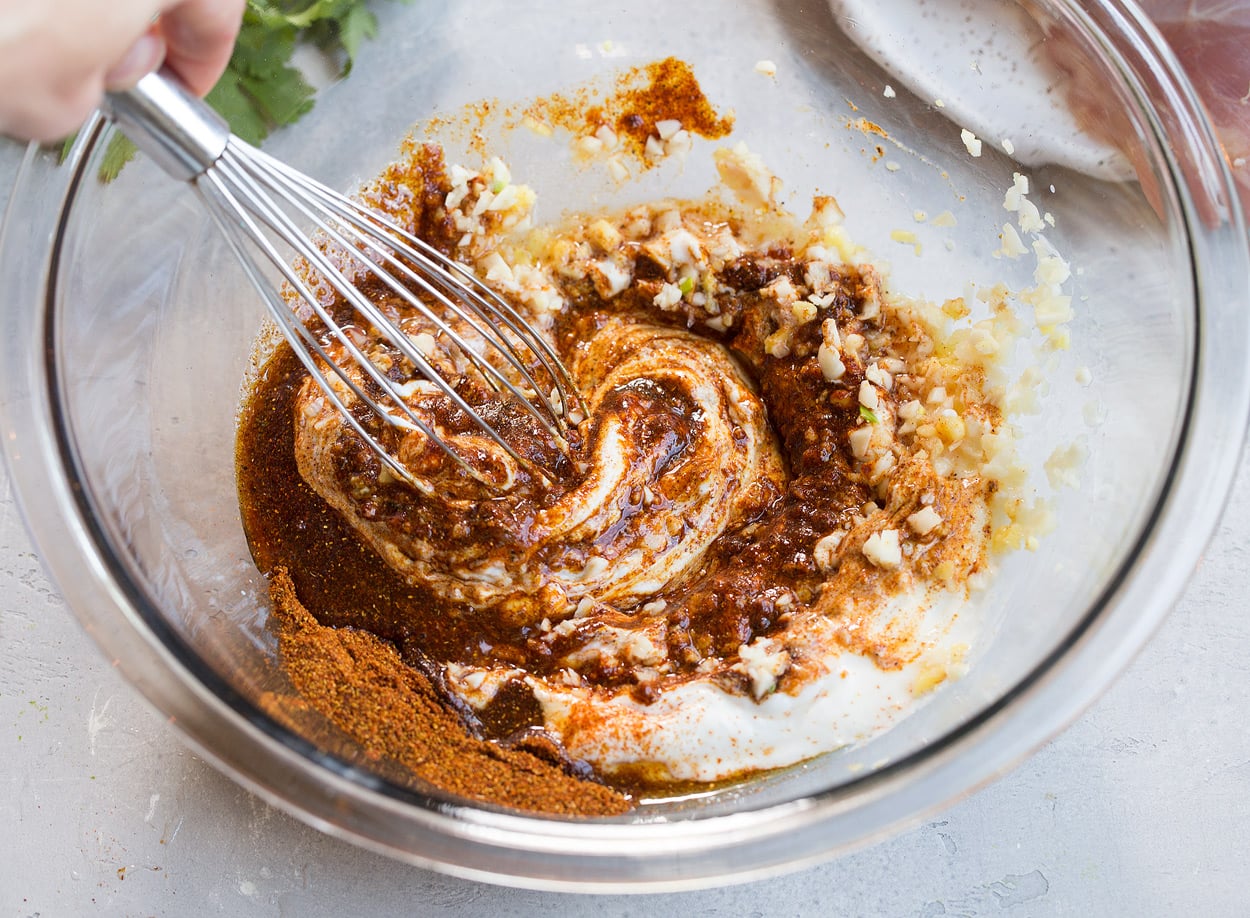 Tandoori Chicken Showing how to make Tandoori Chicken marinade. Whisking yogurt, spices, garlic and ginger in a glass mixing bowl.