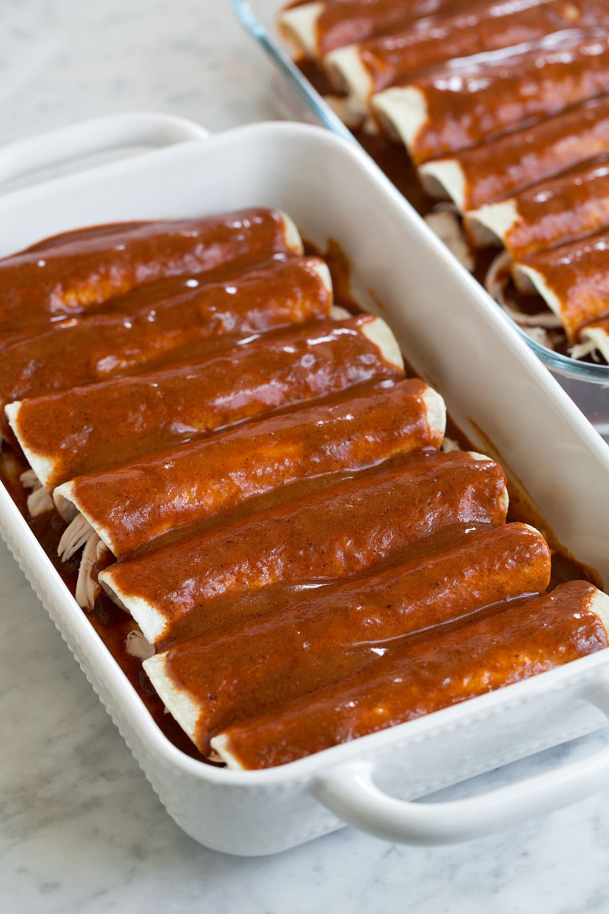 two pans of chicken enchiladas before baking