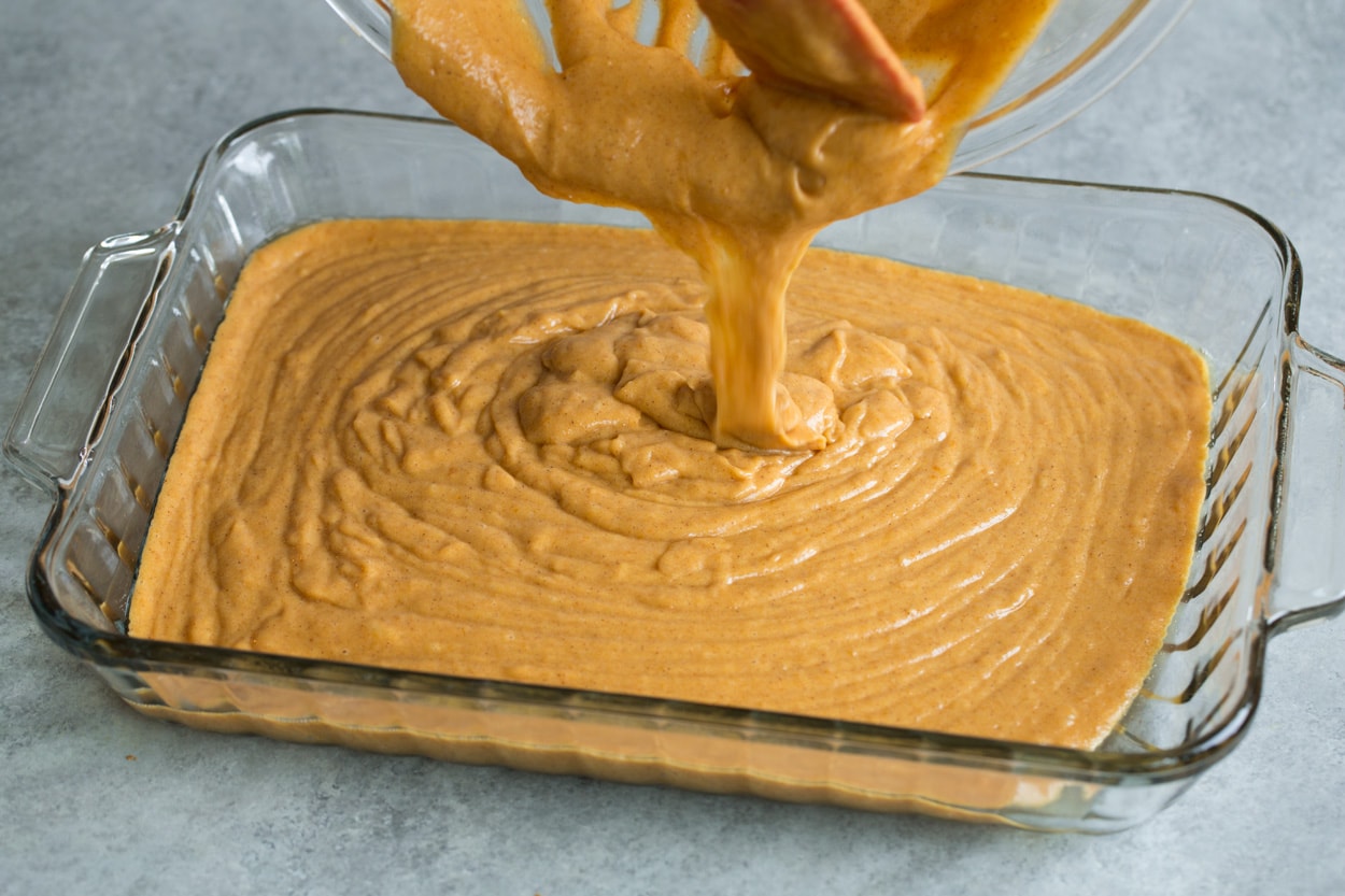 Pumpkin Cake shown here pouring batter into glass cake pan