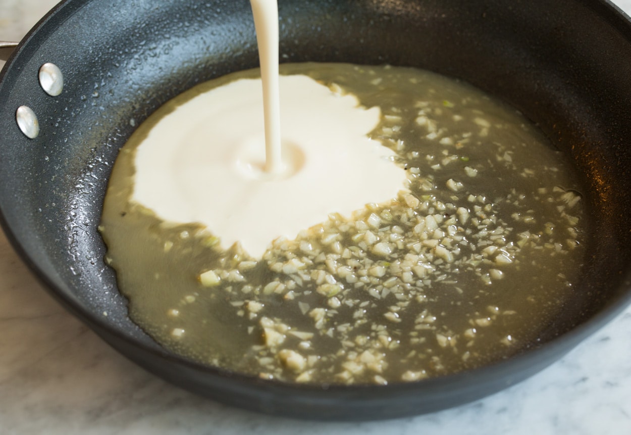 Salmon with Creamy Garlic Dijon Sauce Making pan seared salmon mixing chicken broth and heavy cream mixture in skillet.