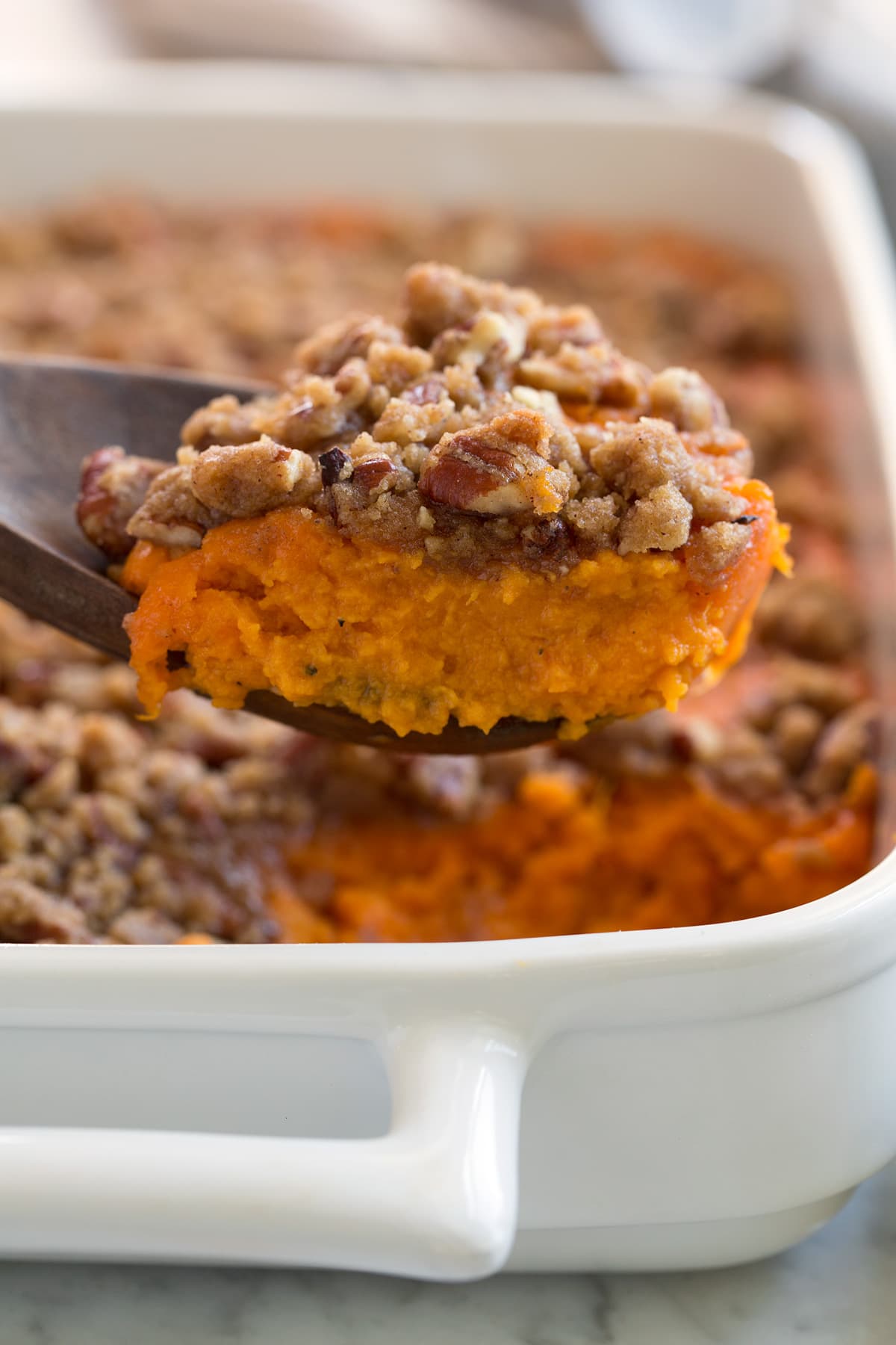 Sweet Potato Casserole Close up image of a scoop of sweet potato casserole showing creamy orange sweet potato layer and a crisp, sugary pecan crumble.
