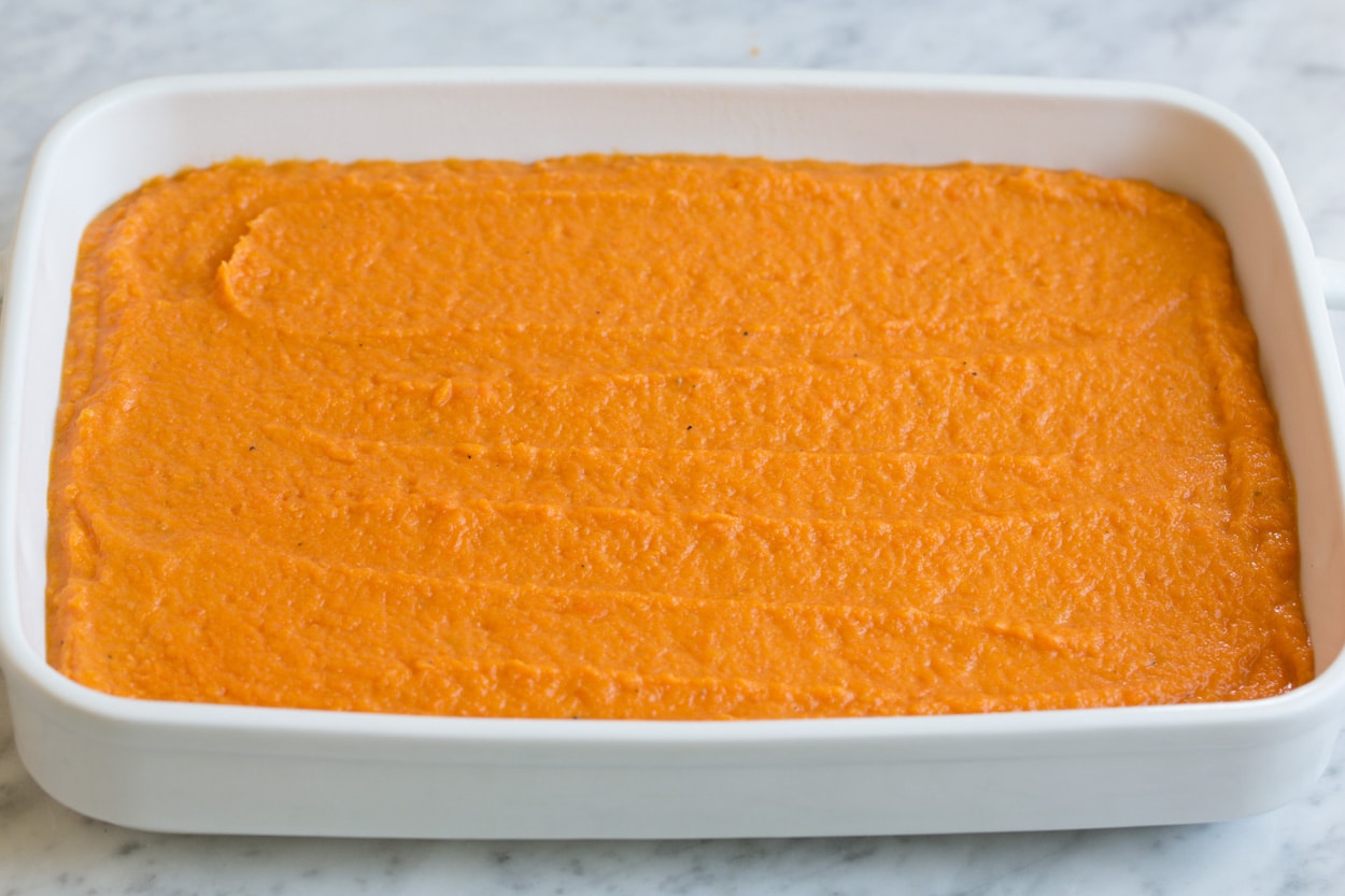 Sweet Potato Casserole Sweet potato layer spread into white ceramic baking dish for sweet potato casserole.