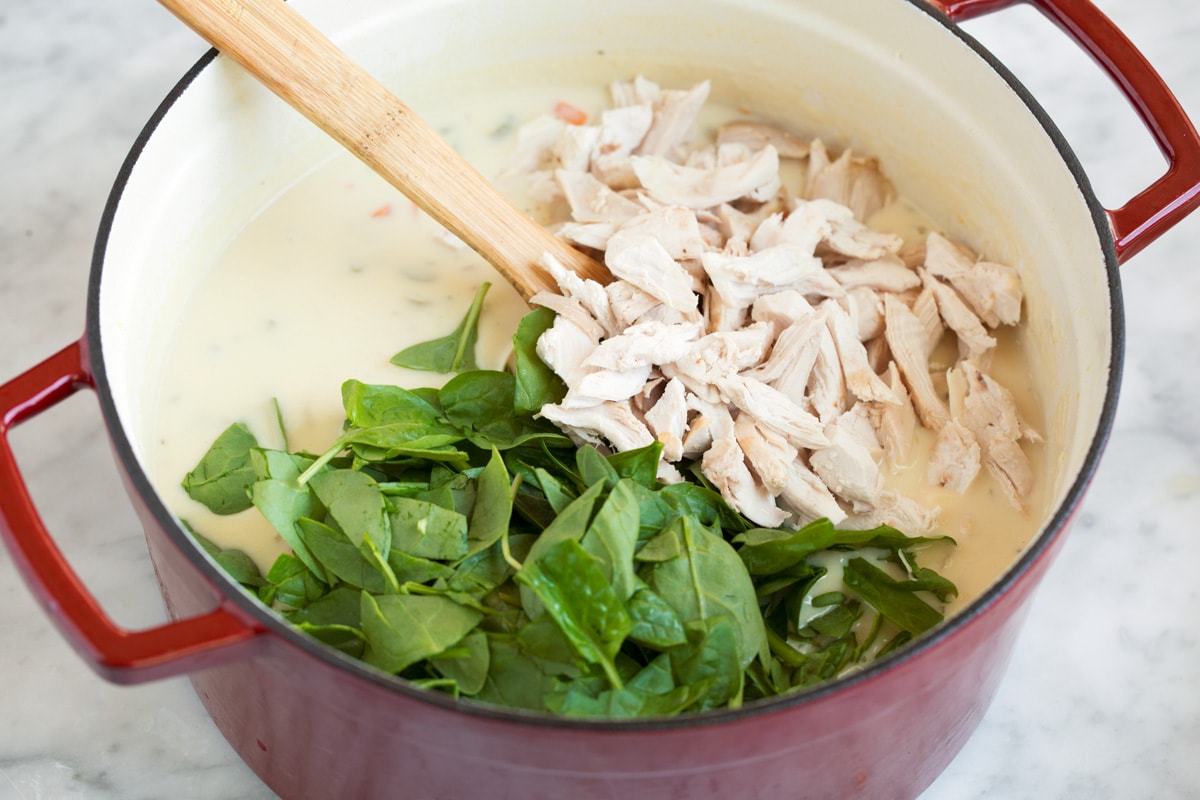 Creamy Chicken Gnocchi Soup Adding cooked shredded chicken and spinach to pot.