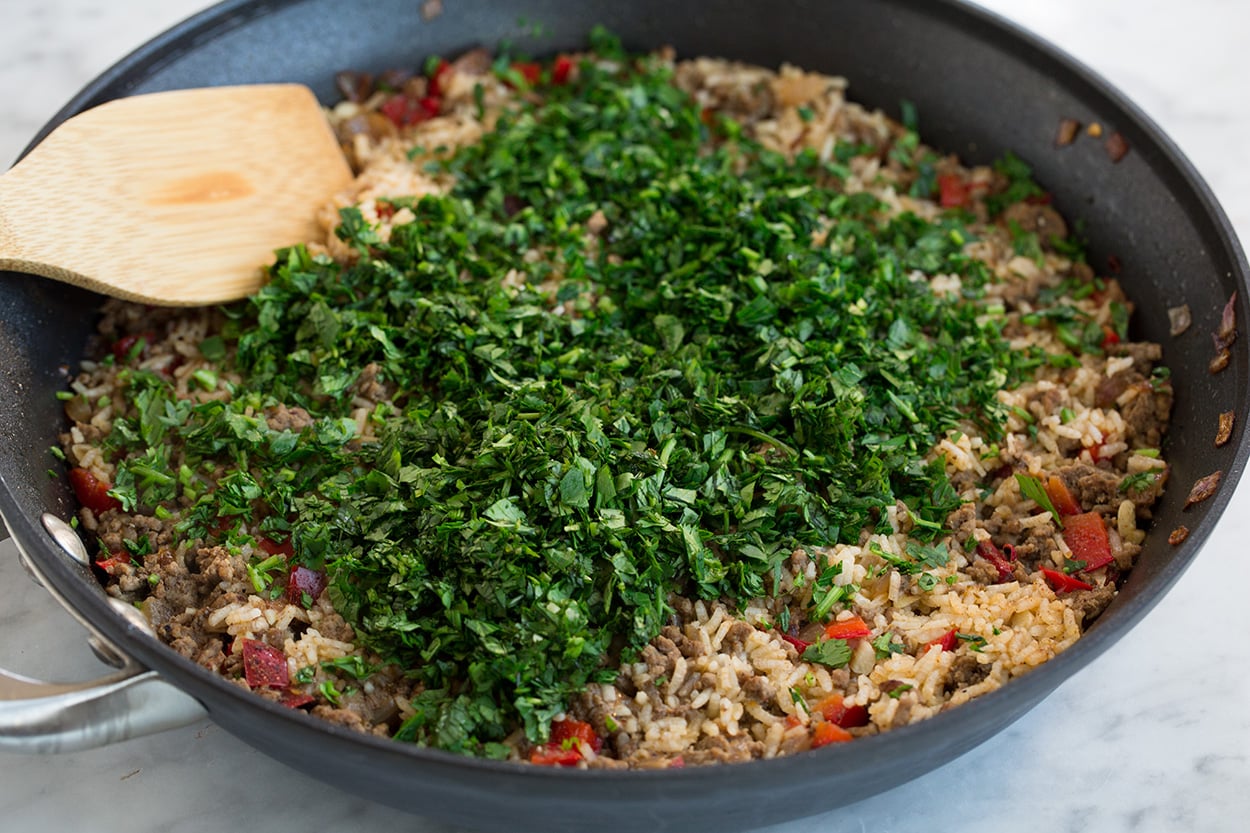 Chimichurri Beef and Rice Adding parsley and cilantro to Chimichurri Beef and Rice after cooking.