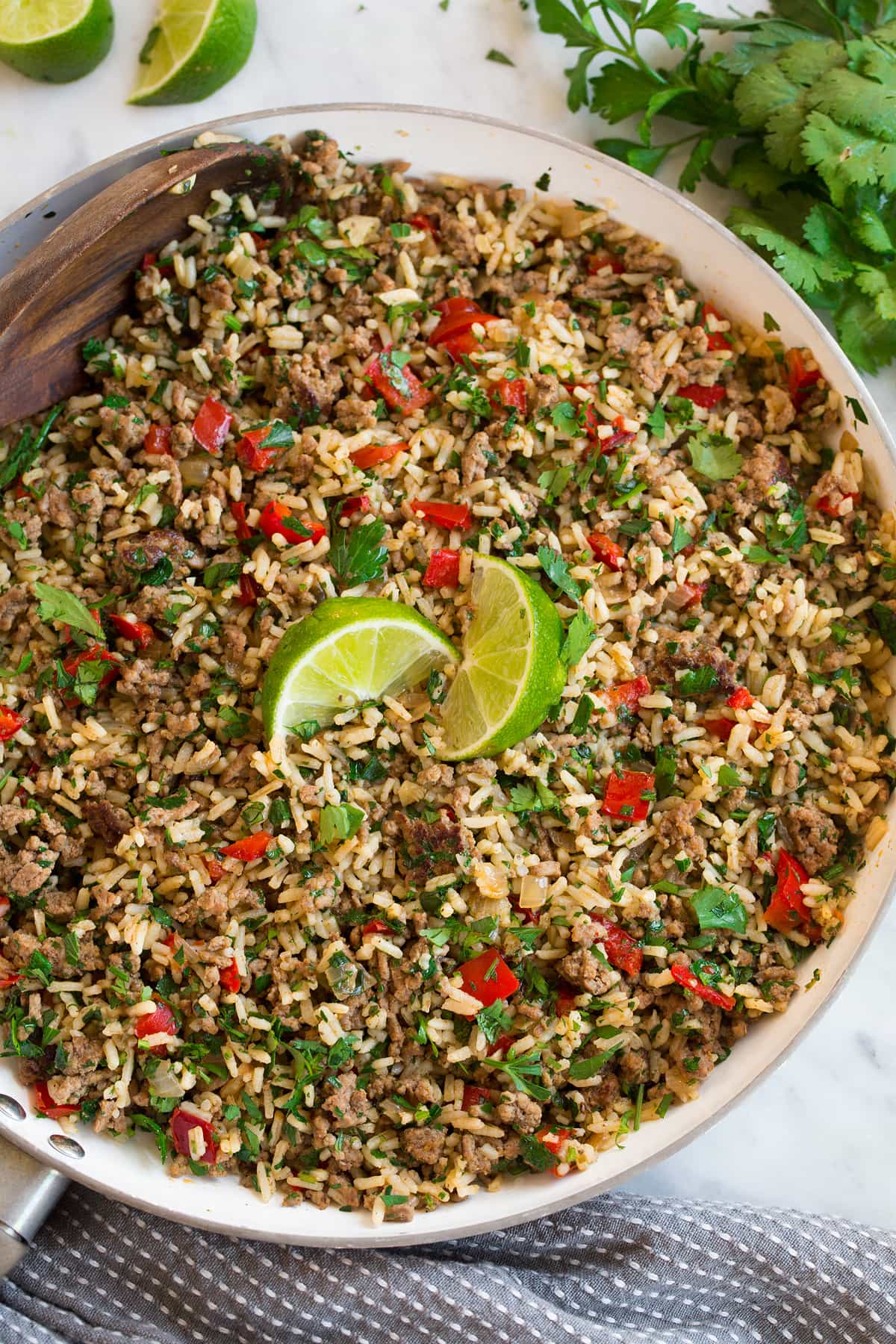 Chimichurri Beef and Rice Overhead image of Chimichurri Beef and Rice in white skillet after completed. It's garnished with lime wedges.