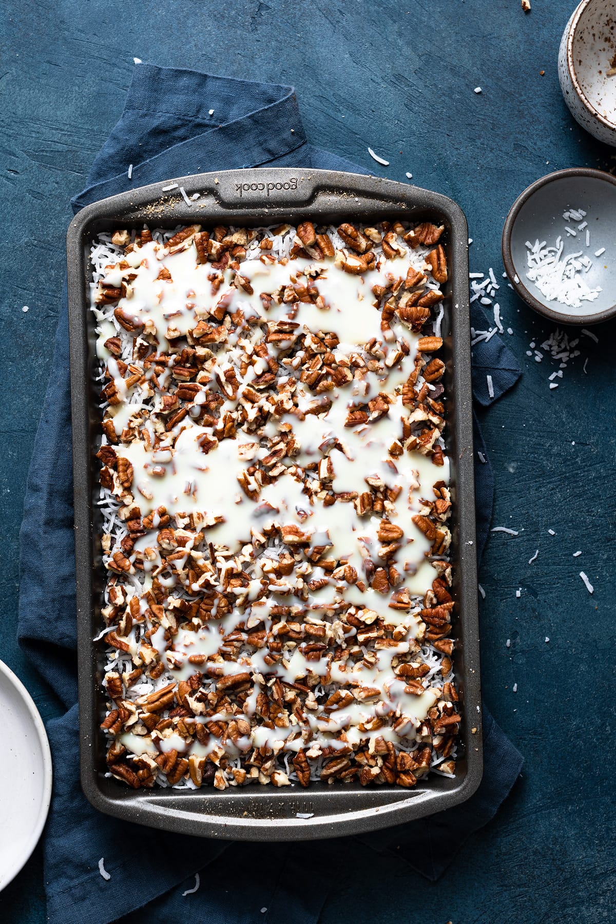 Magic Bars Showing how to make magic bars pouring sweetened condensed milk over chocolate chip layer in baking dish.