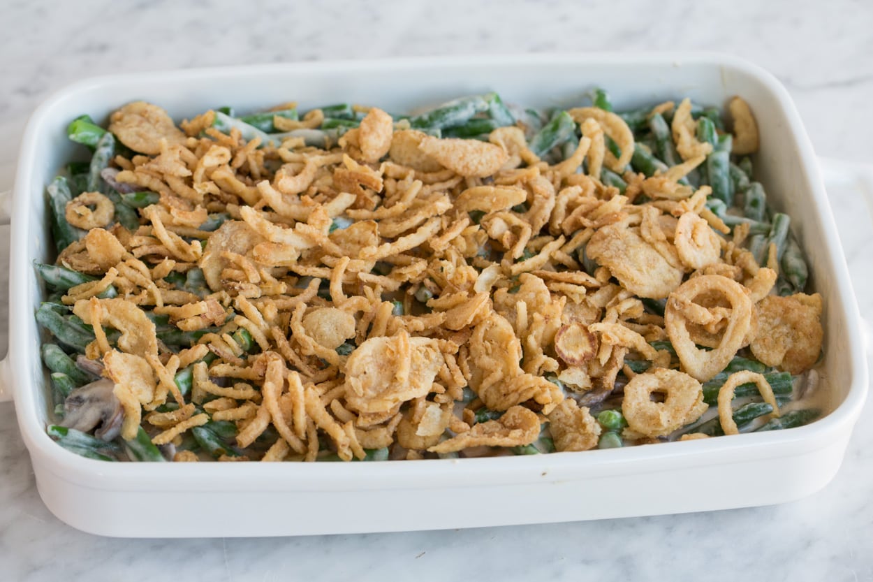 Green Bean Casserole Adding crispy fried onions to Green Bean Casserole before baking.
