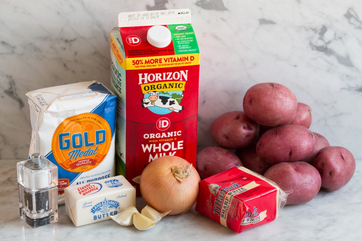 Scalloped Potatoes Ingredients for scalloped potatoes shown here including whole milk, butter, flour, onion, garlic, red potatoes, sharp white cheddar cheese, salt and pepper.