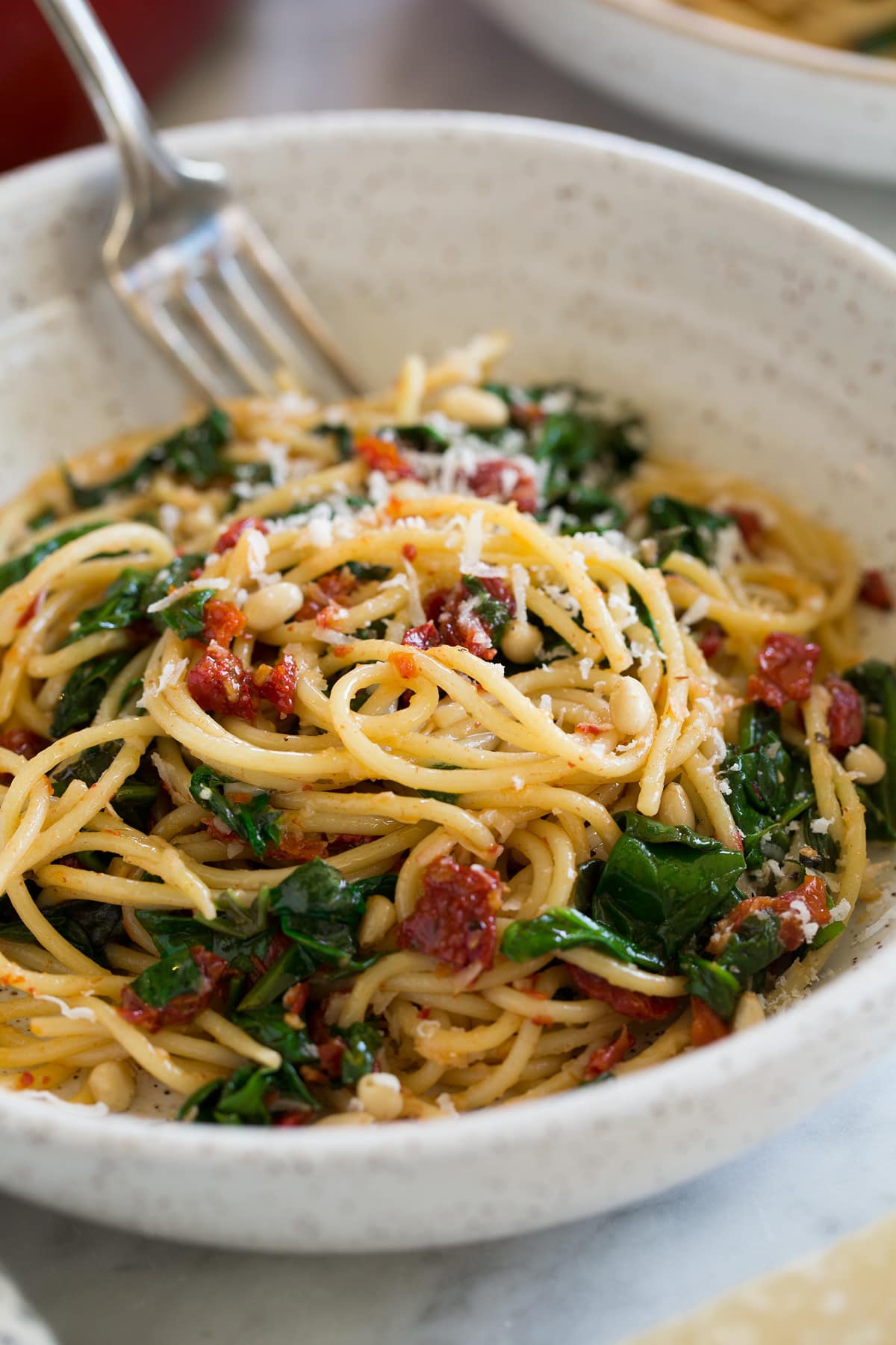 close up of sun dried tomato pasta in white bowl with fork