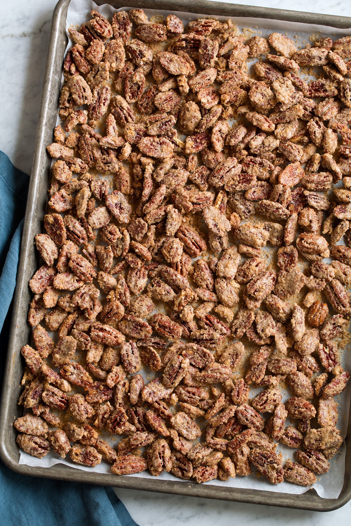 Candied Pecans Finished candied pecans on a parchment paper lined baking sheet.