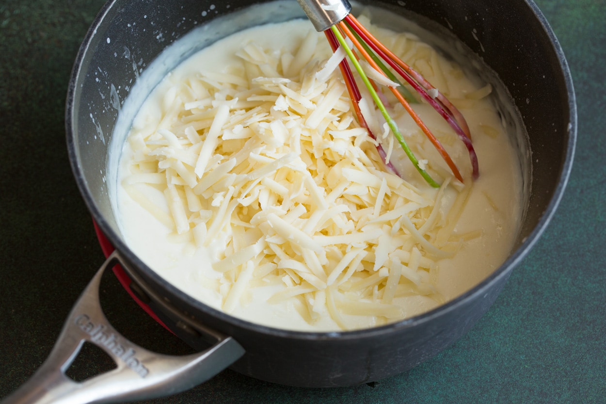 Cauliflower Soup Adding cheese to milk mixture in saucepan.