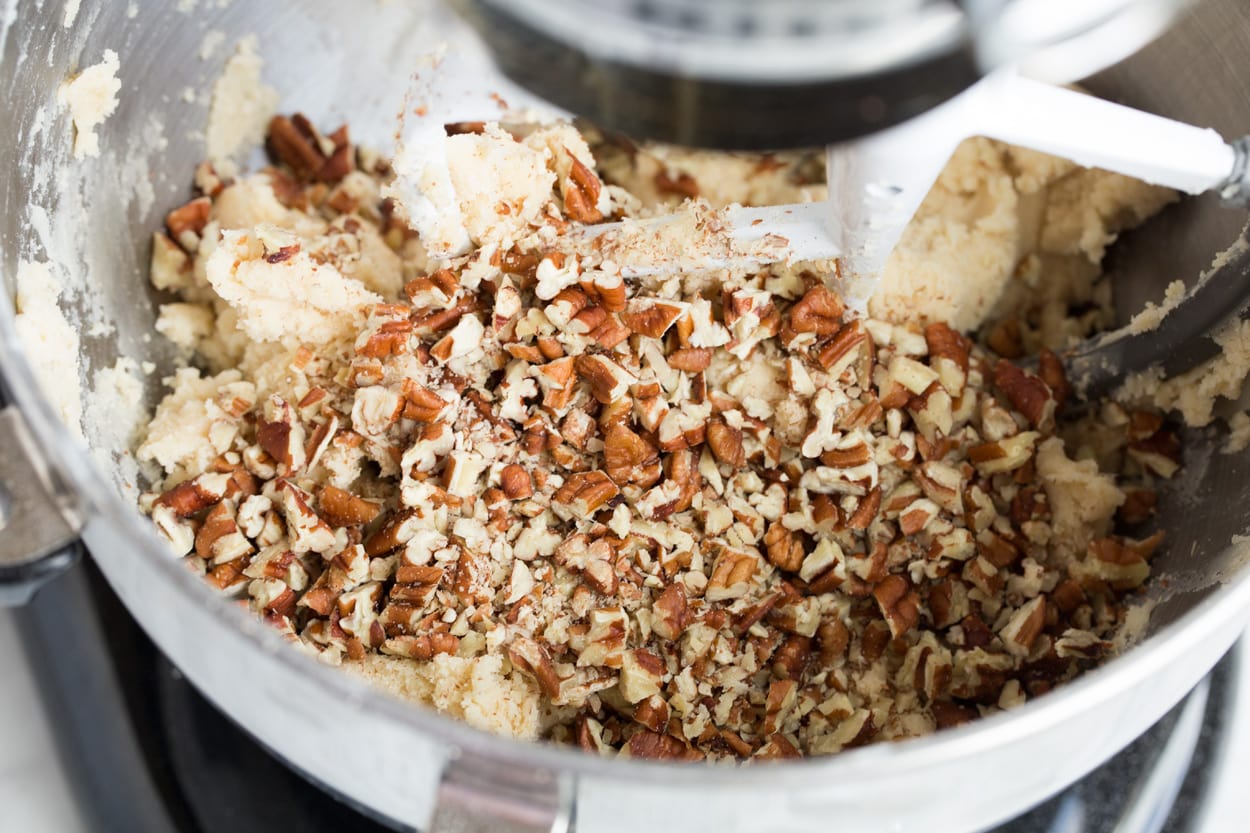 Mexican Wedding Cookies Adding Pecans to Mexican Wedding Cookie batter in stand mixing bowl.