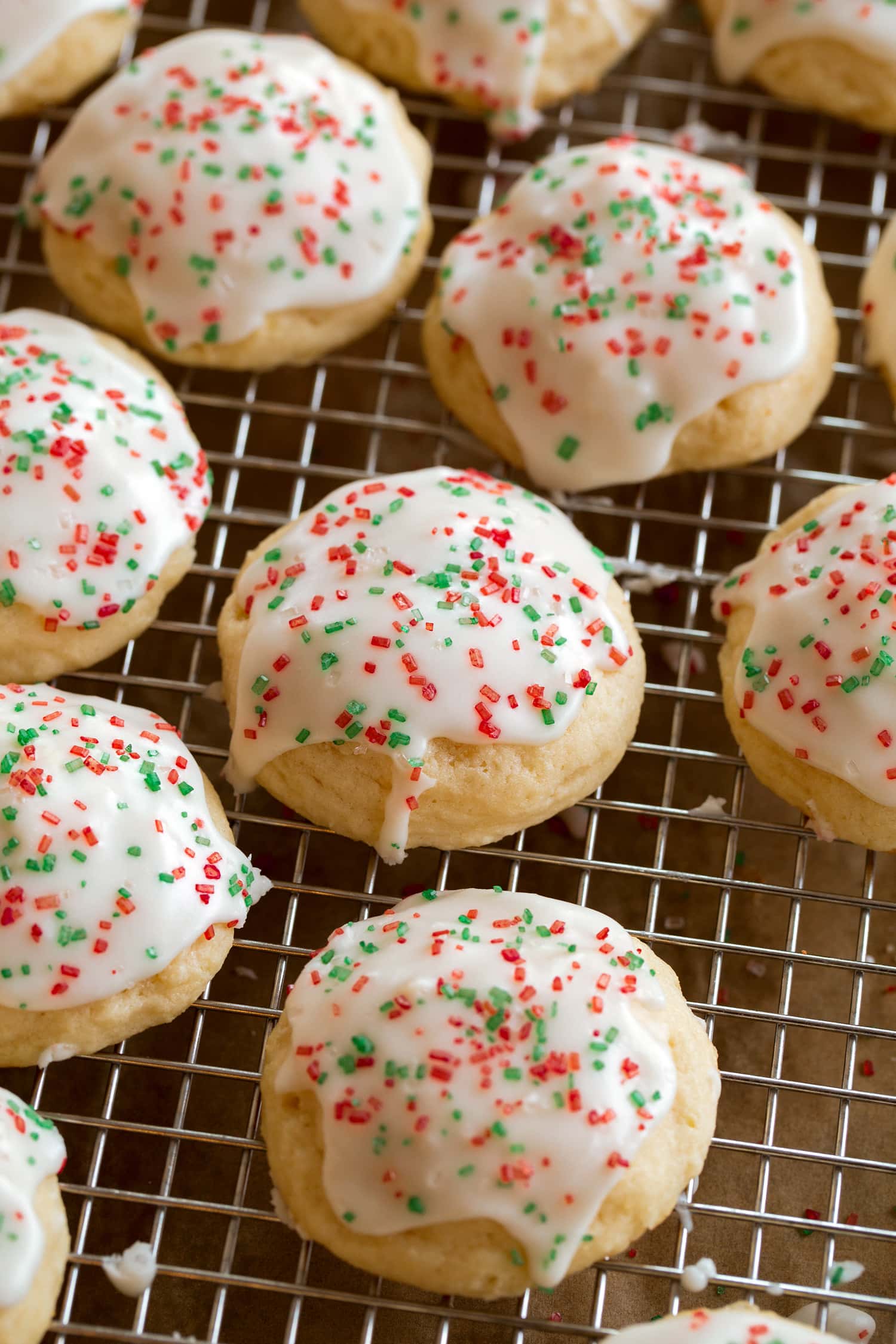 Ricotta Cookies Close up photo of Christmas cookies on a cooling rack after covering with icing.
