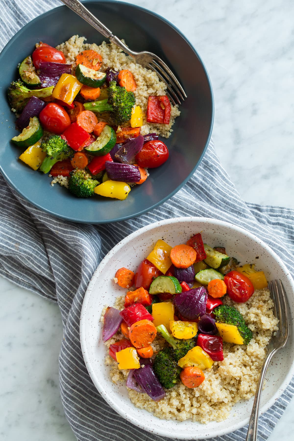 Roasted Vegetables Roasted Vegetables served over quinoa with lemon in two serving bowls.