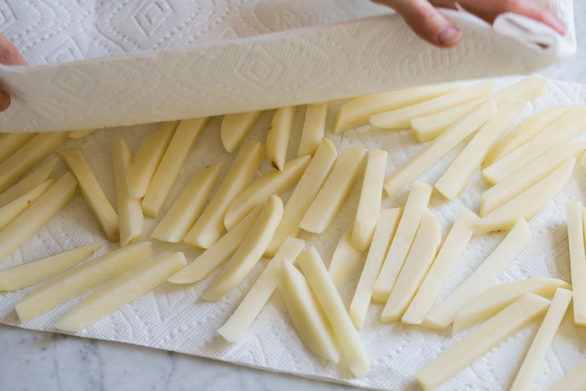 Baked French Fries Drying potato sticks with paper towels.
