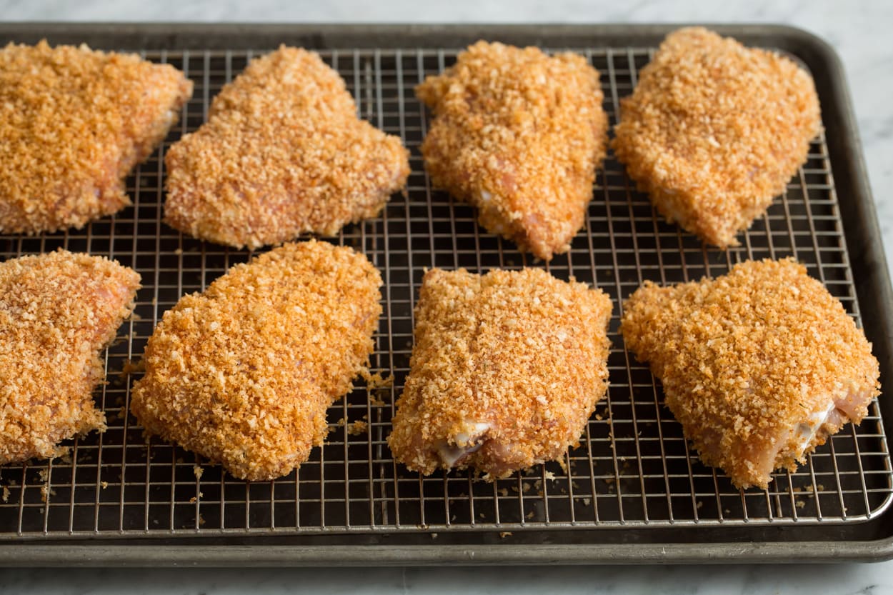 Oven Fried Chicken Eight panko and olive oil coated chicken thighs on a wire cooling rack set over a baking sheet before baking.